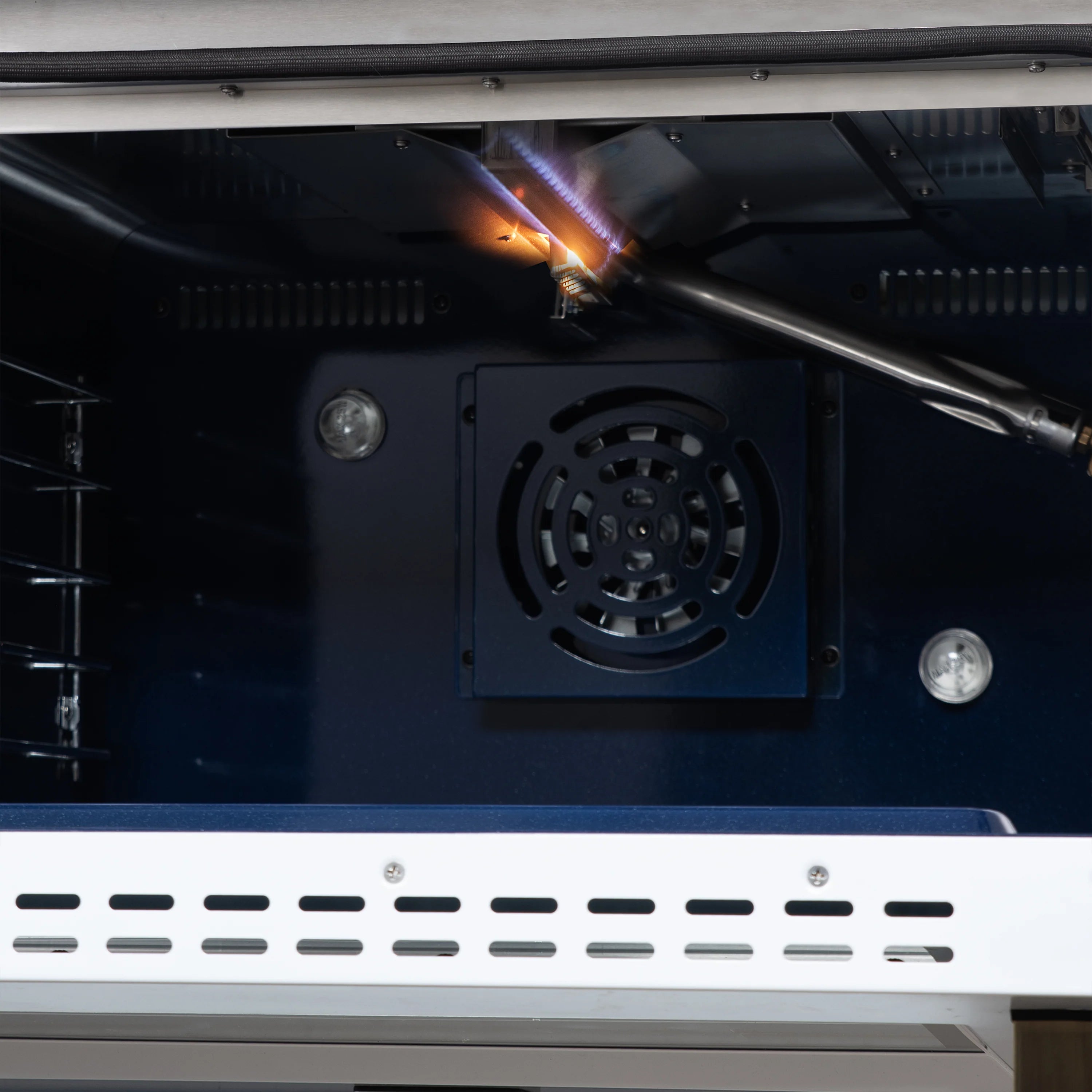 Convection oven interior with fan housing and glowing heating element above.
