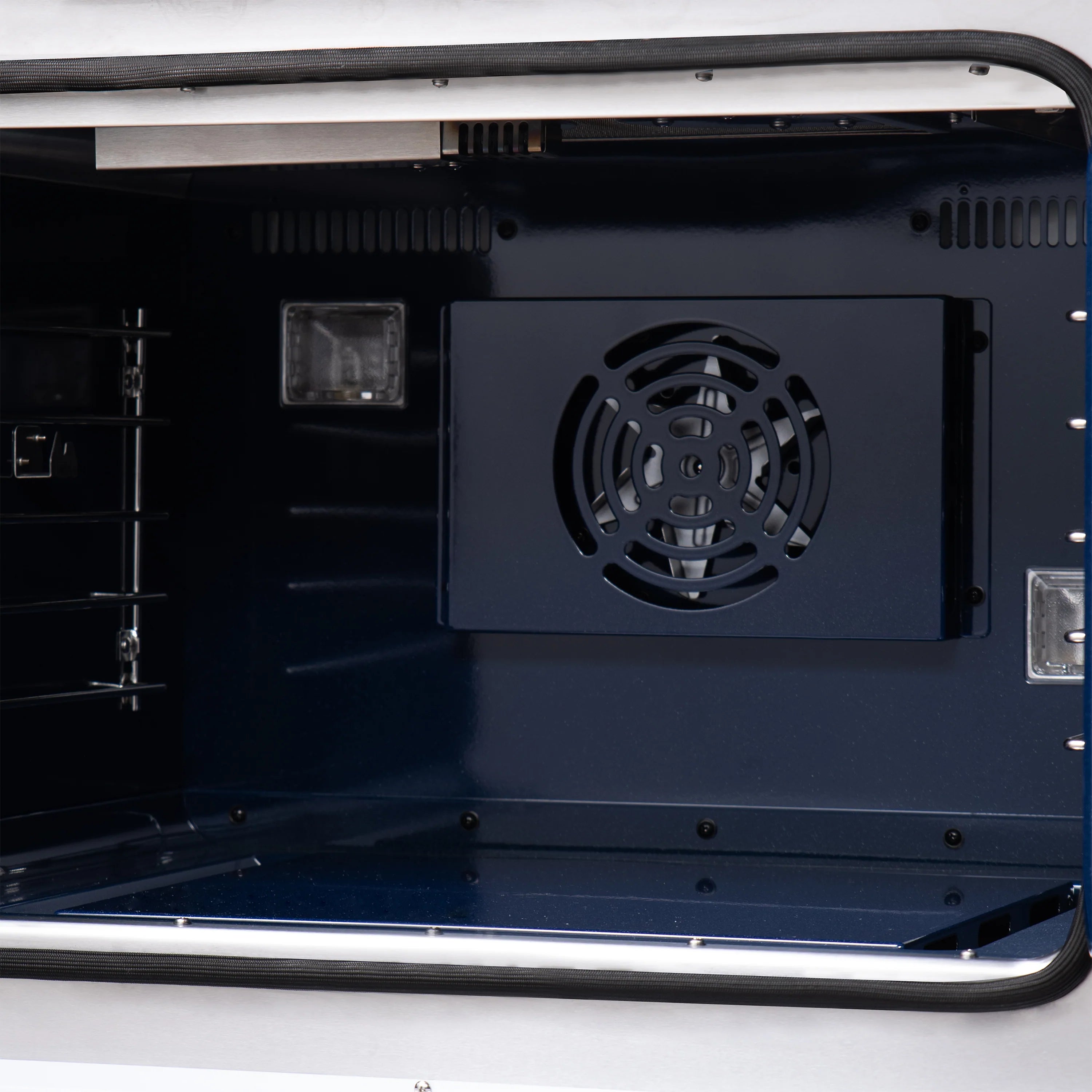 Gas oven interior with rear fan vent and metal rack supports