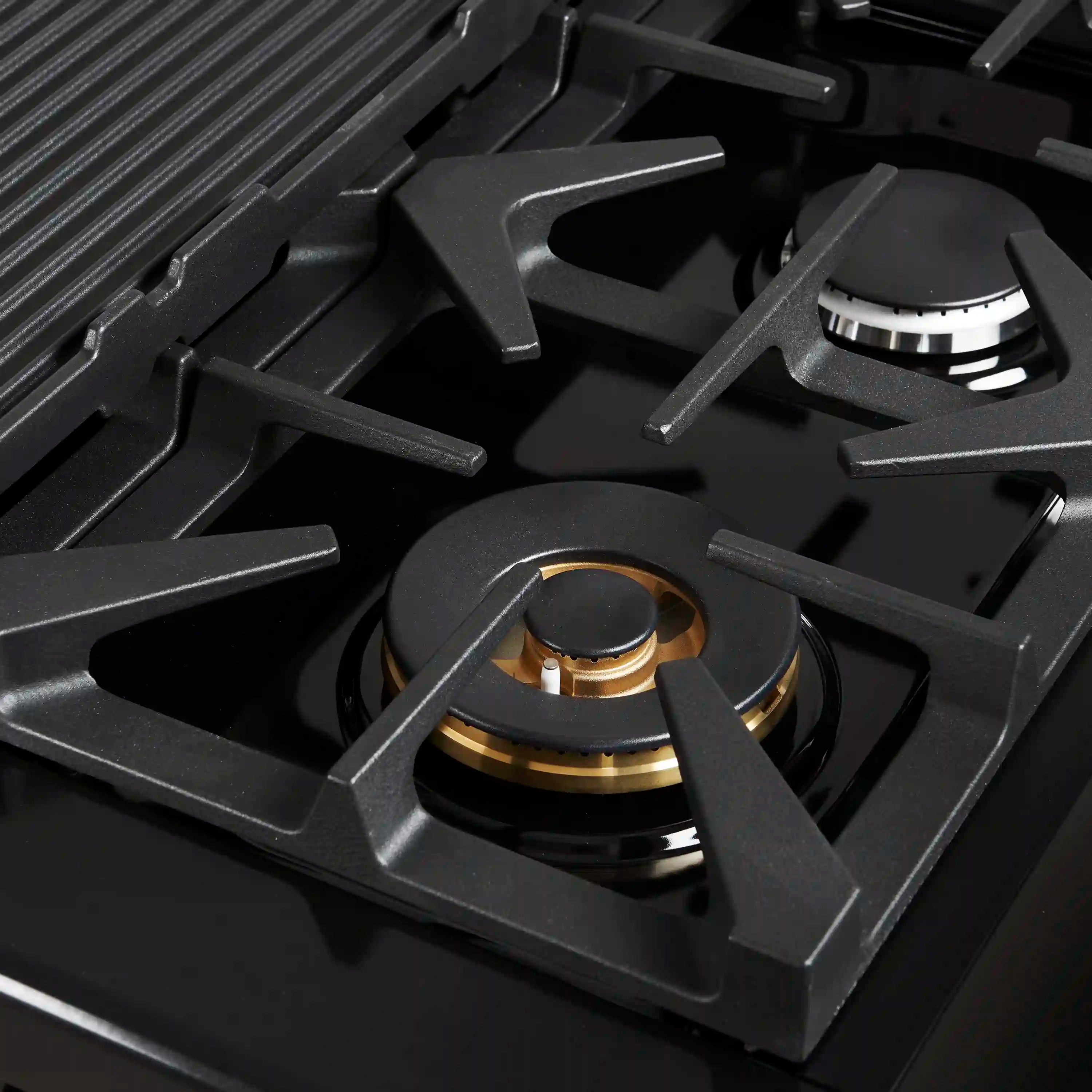 Black gas cooktop burner with brass cap and cast-iron grate
