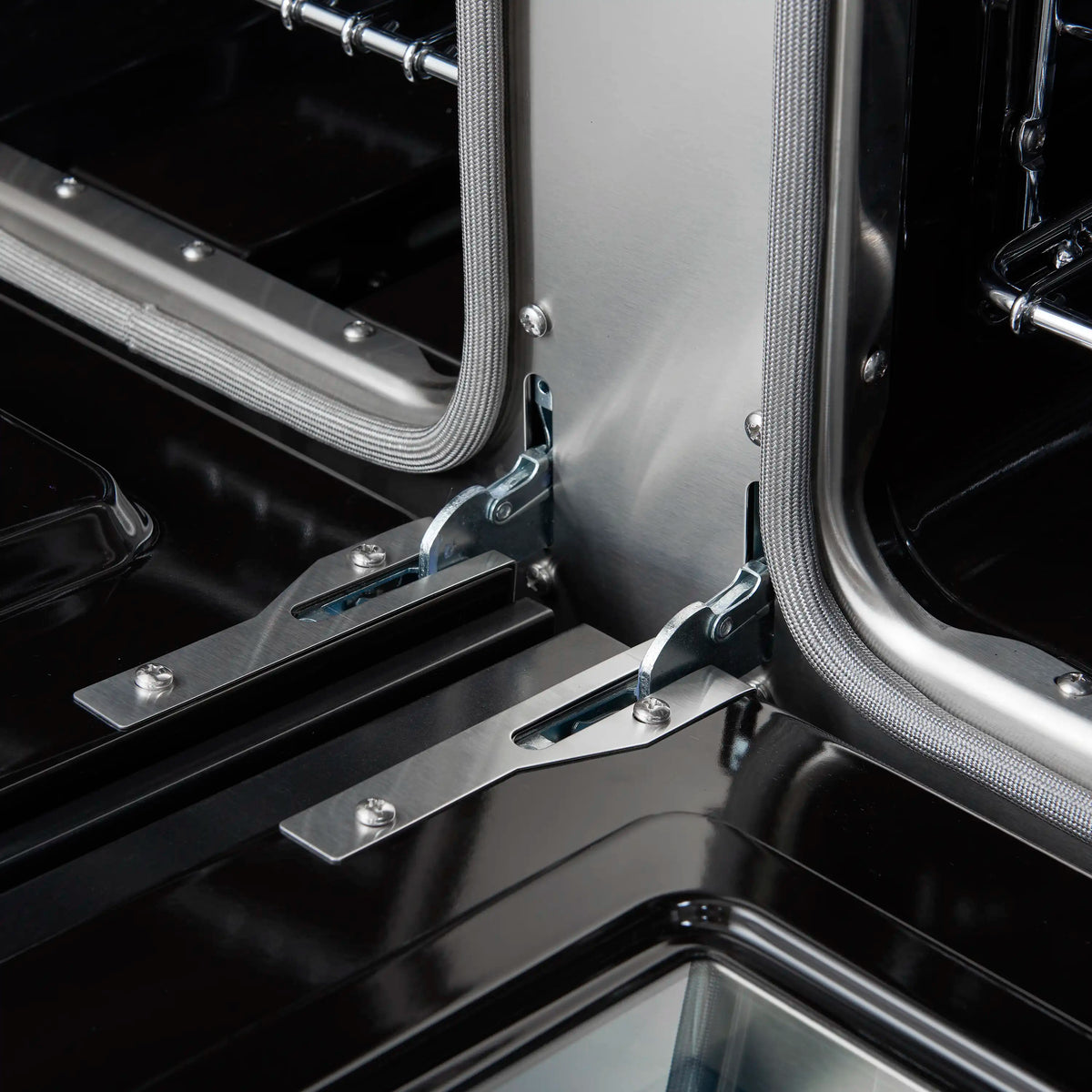 Close-up of oven door hinge and flexible gasket on a black range