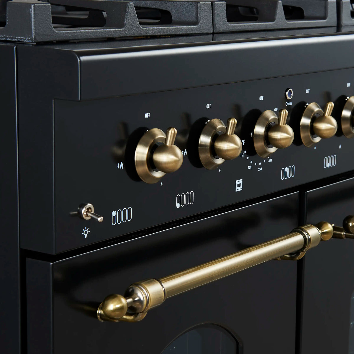 Black gas range control panel with antique brass knobs and burner icons