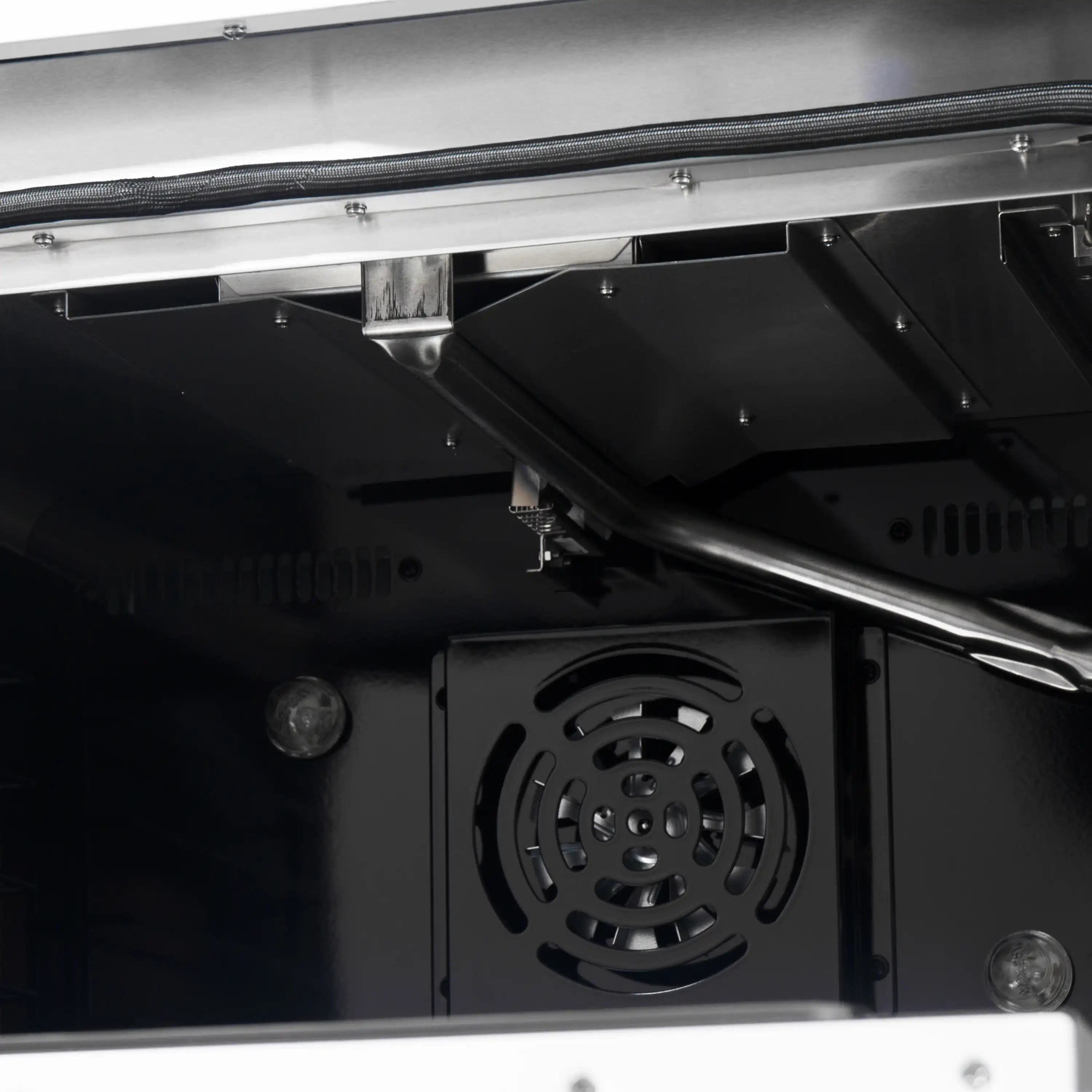 Inside view of a white gas range with top burner cover and rear heat fan