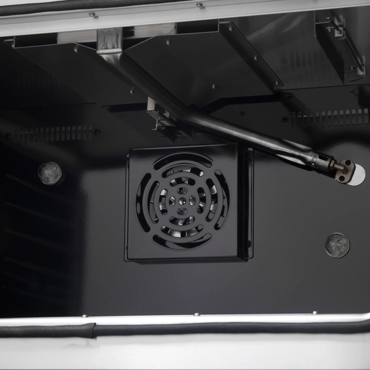 Black range hood interior with square fan grille and metal duct outlet
