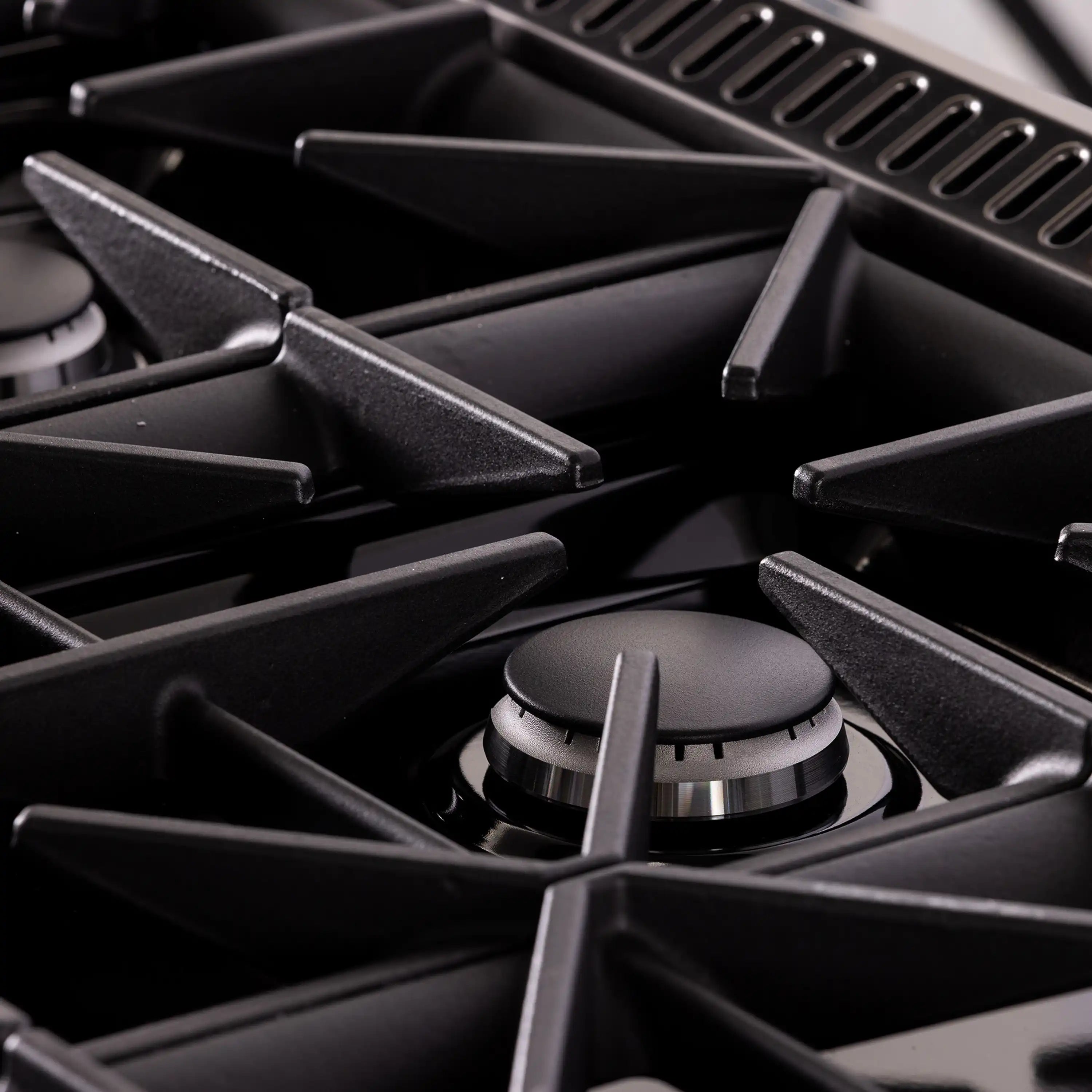 Gas burner grates and dark titanium control knobs on a dual fuel range top
