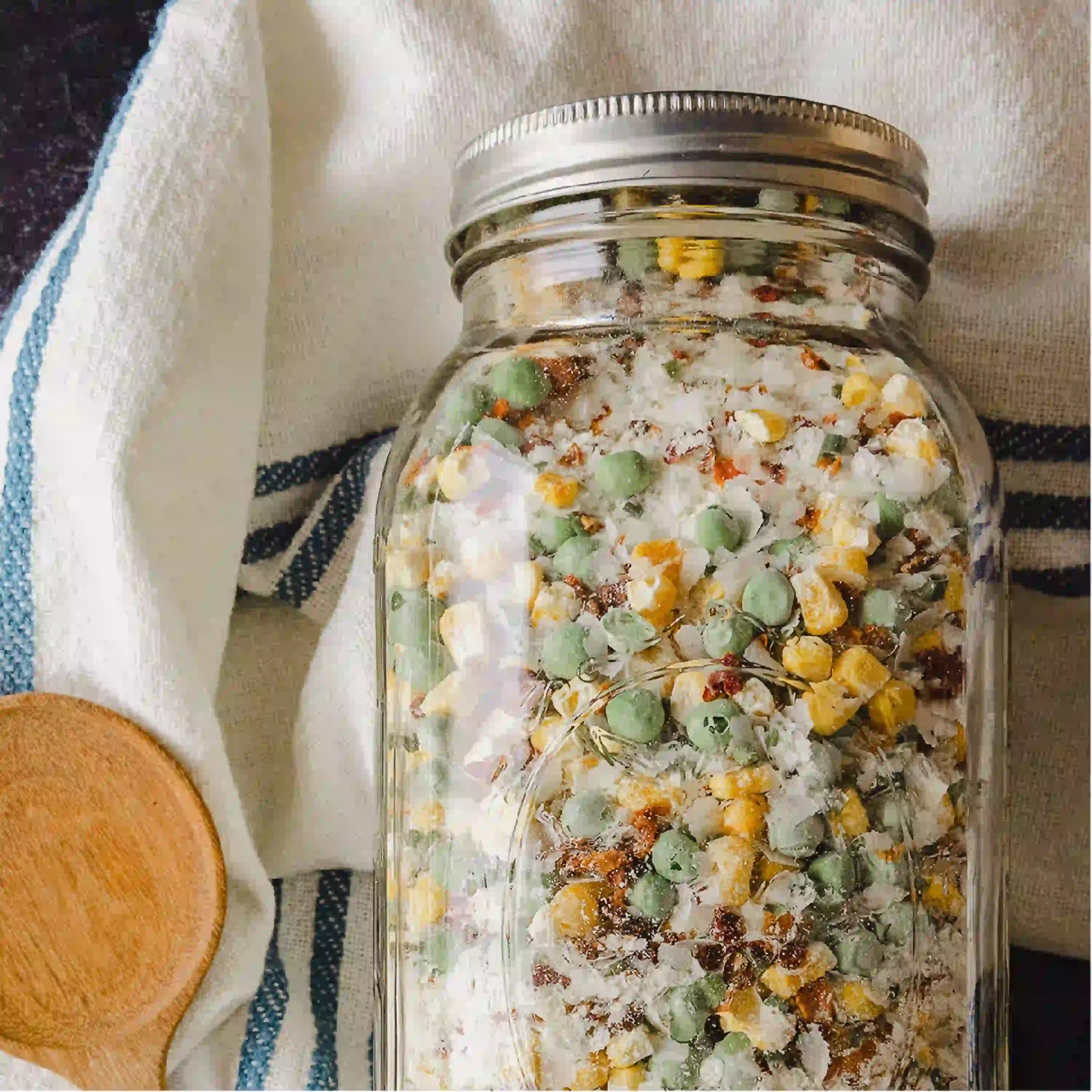 Glass jar filled with preserved green and yellow vegetable pieces for long storage.