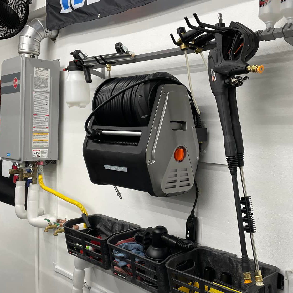 Retractable pressure washer with spray wand and coiled hose mounted in a utility area
