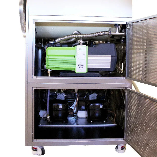 Commercial freeze dryer interior with compressor units and vacuum lines, access door open