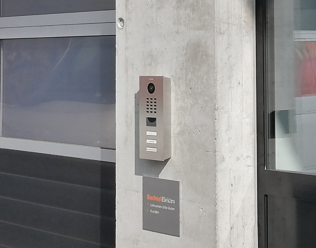 Wall-mounted video door station with camera, call buttons, and display window