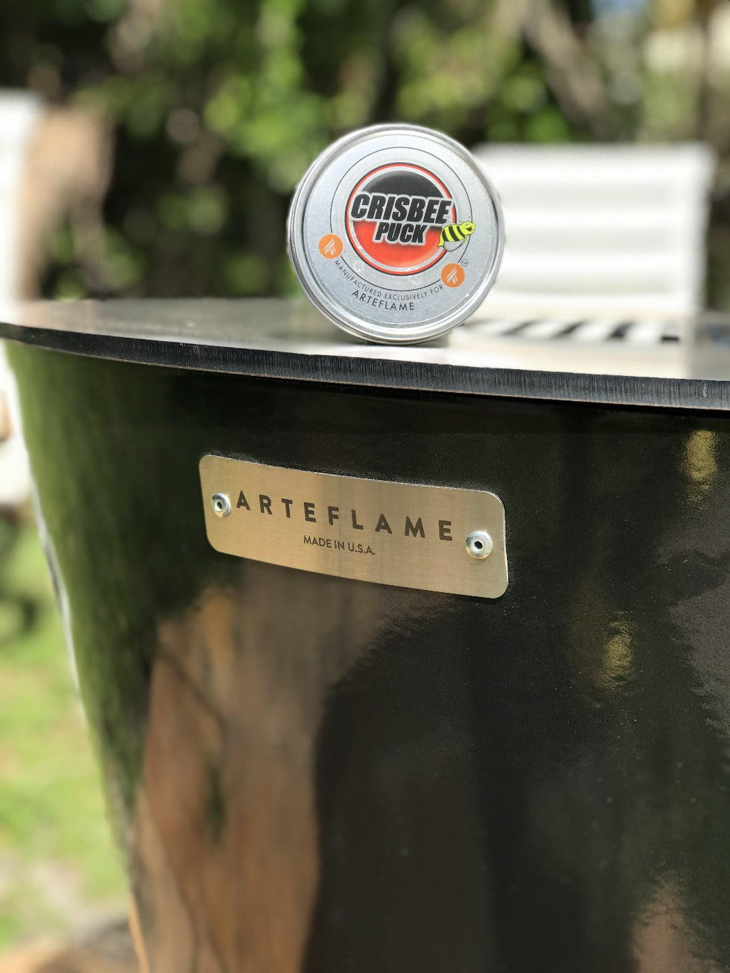 Crisbee Puck seasoning puck tin on Arteflame grill lid, round silver container
