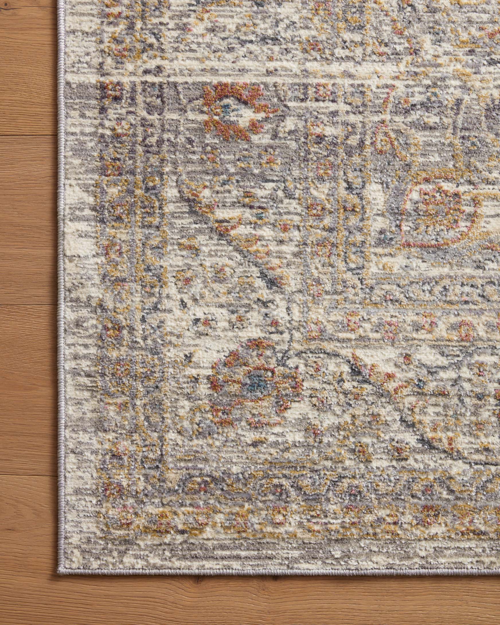 Stone area rug close-up with woven distressed motif and dark multicolor accents