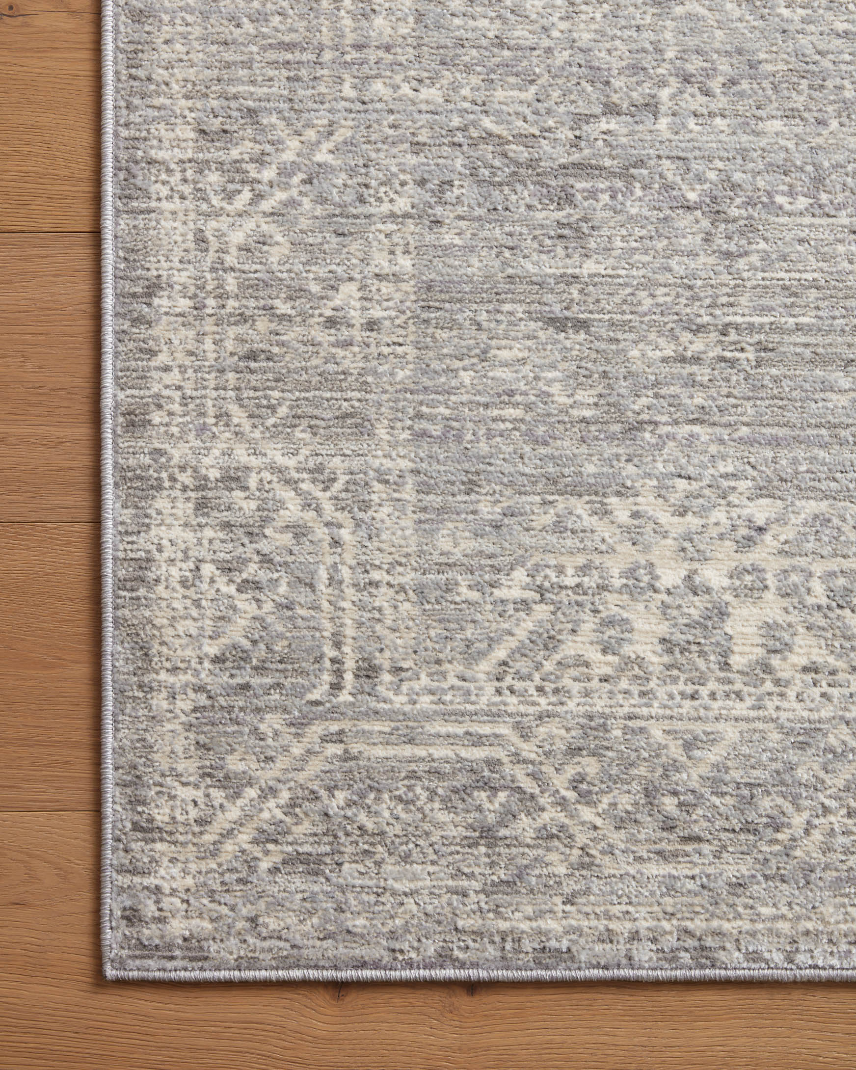 Silver and ivory rug close-up with textured distressed pattern and low, even pile