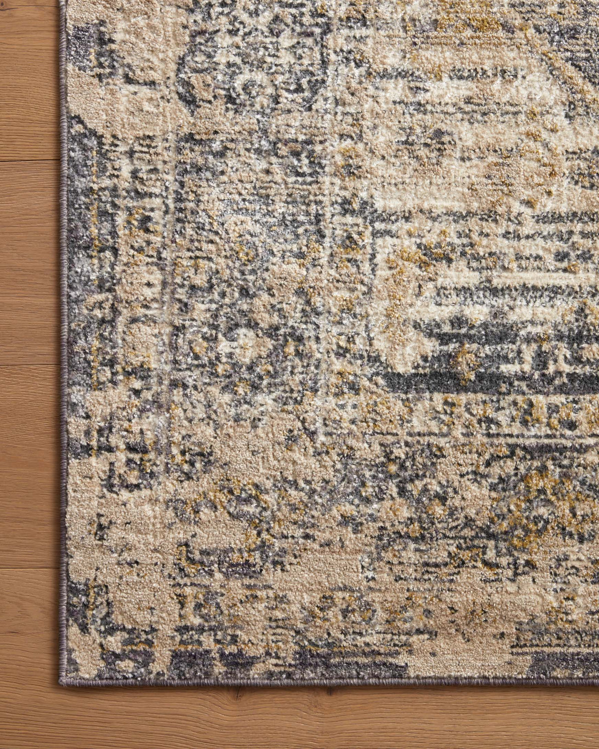 Charcoal and natural rug corner with close-up distressed texture and patterned border