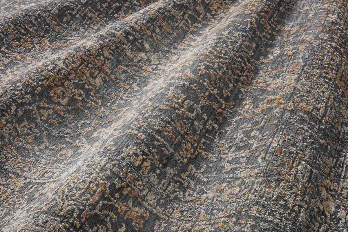 Textured area rug close-up with dark gray, blue, and tan distressed motif, short pile.