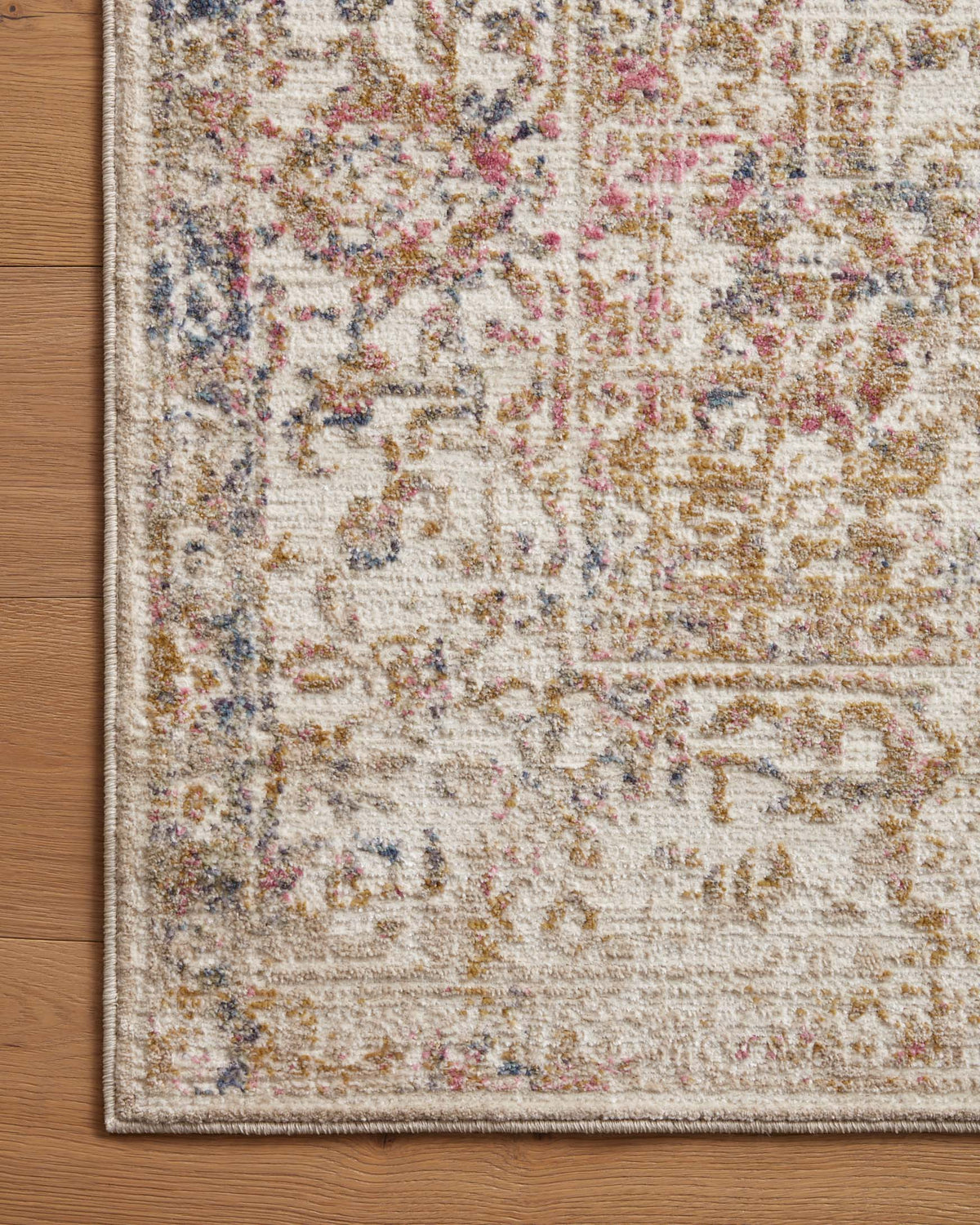 Ivory area rug close-up with multicolor distressed pattern and textured border edge