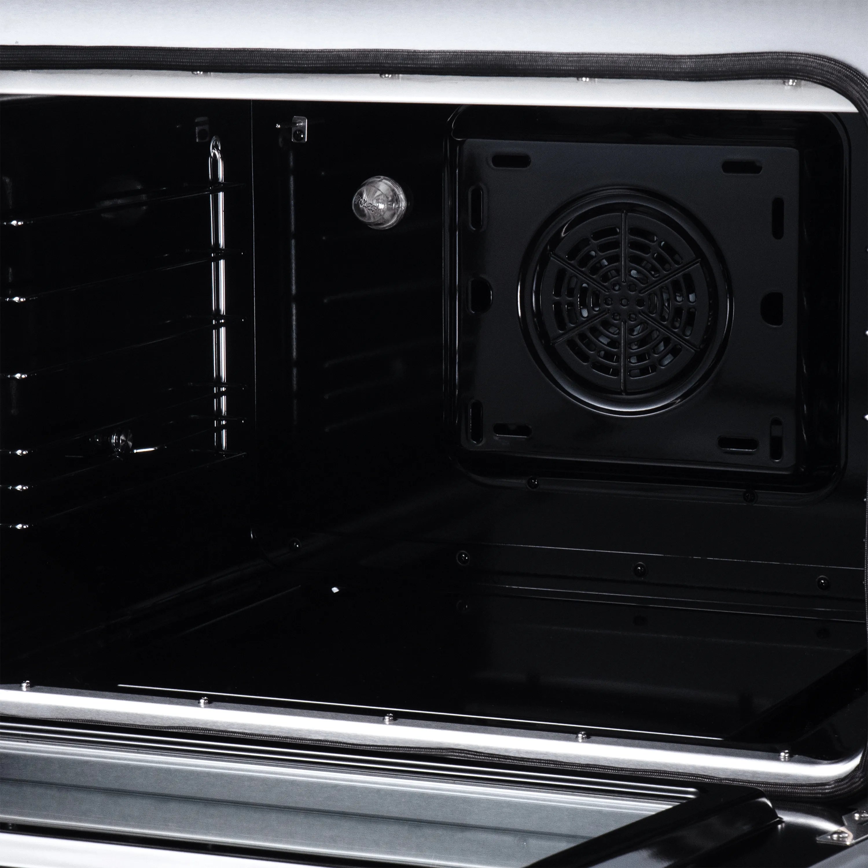 Open oven interior with black cavity, fan vent, and wire racks inside the range