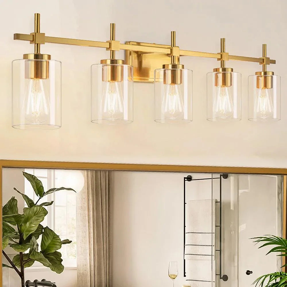 5-light vanity light with clear glass shades and gold frame above mirror
