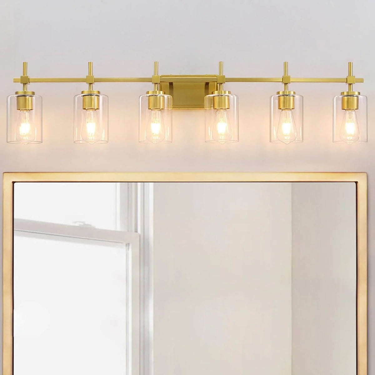 Golden 6-light bathroom vanity light with clear glass shades against wall