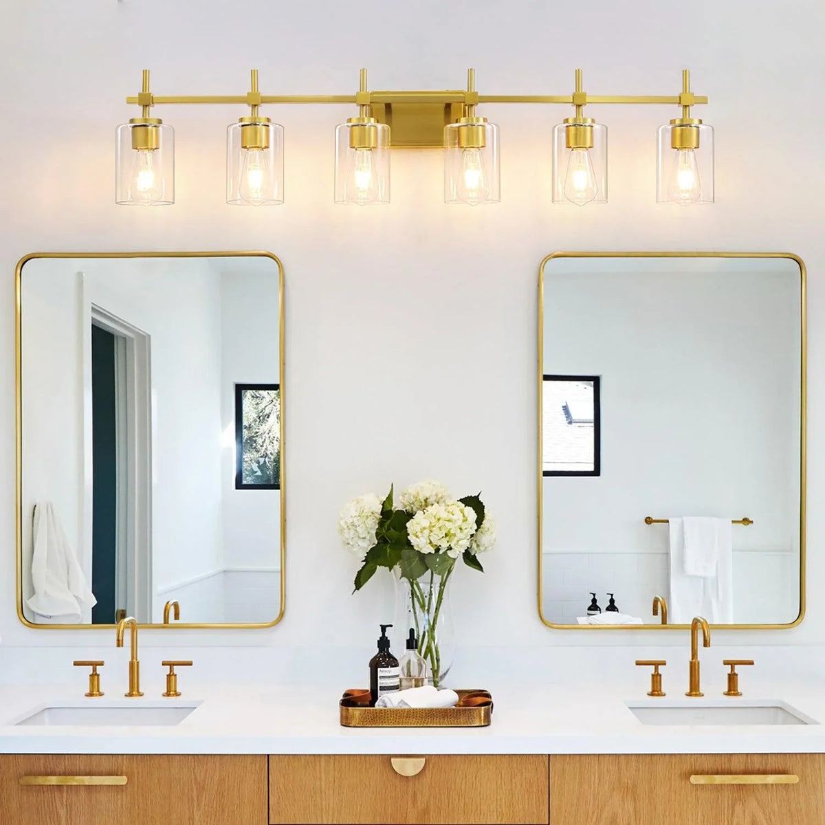 Bathroom vanity light with six clear glass shades on a golden metal bar