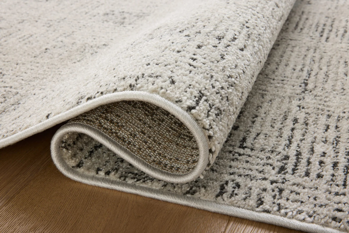 Transitional accent rug corner, rolled edge with light gray pile and dark backing