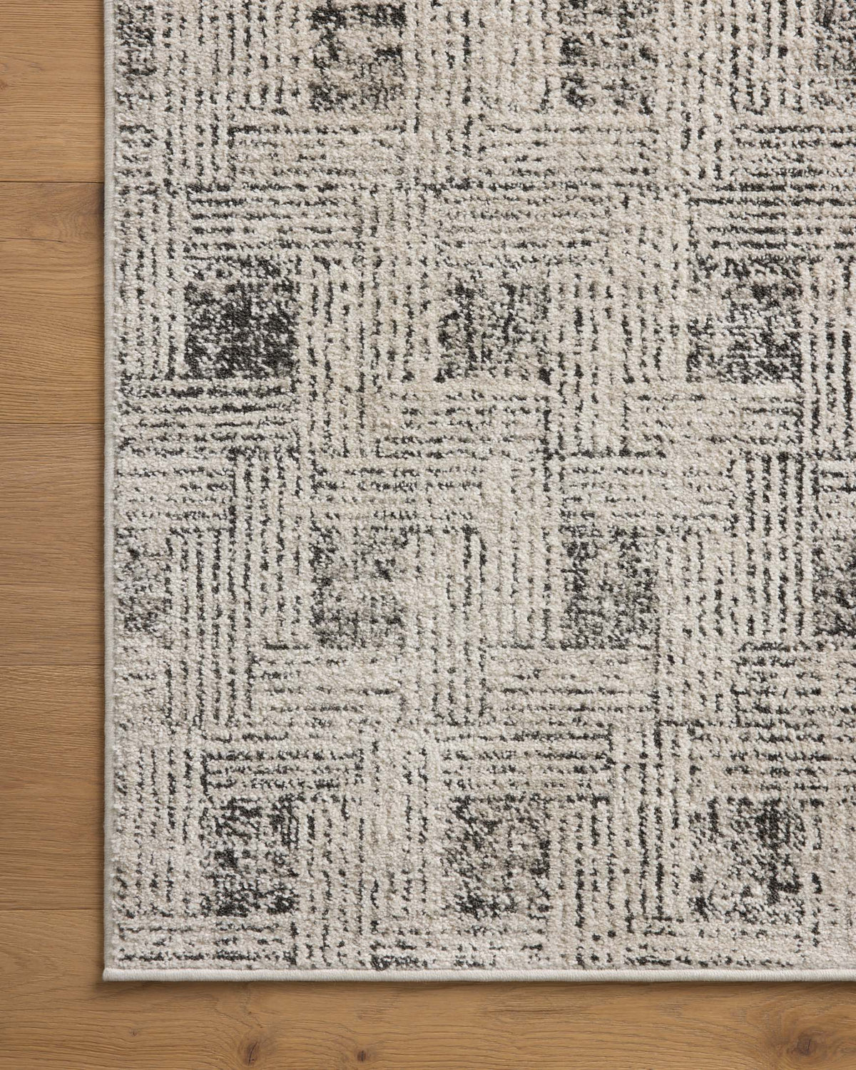 Transitional area rug with ivory field and distressed grey blocks near a bound border