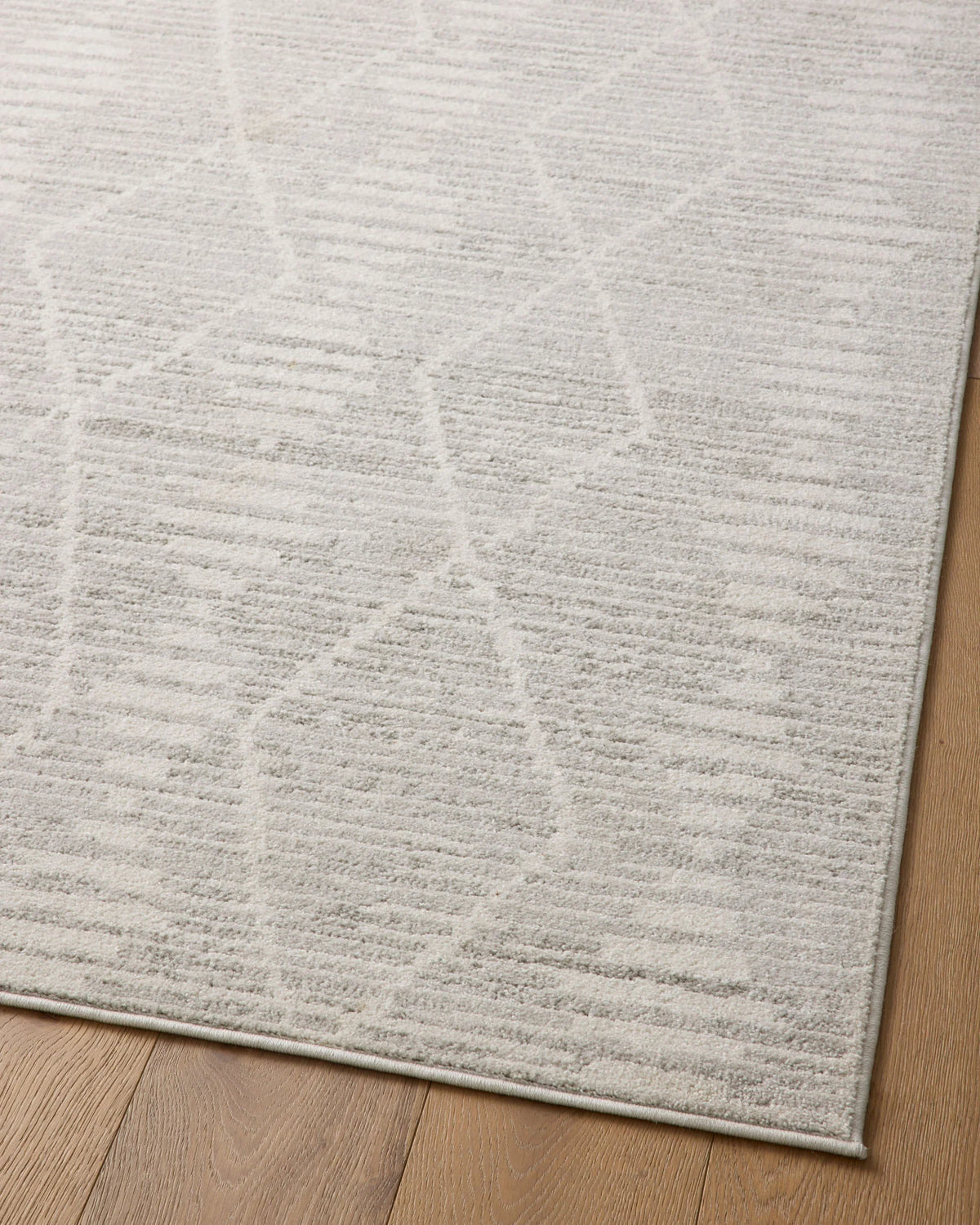 Ivory and silver area rug with detailed abstract geometric texture near corner.