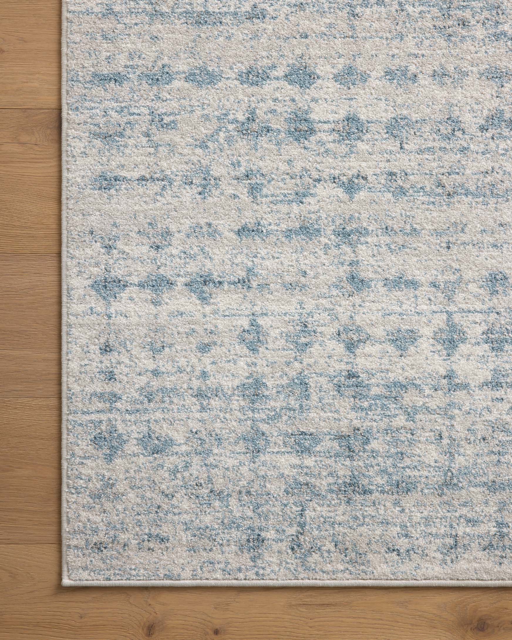 Rectangular area rug with light blue and dove-gray distressed pattern and bound border edge