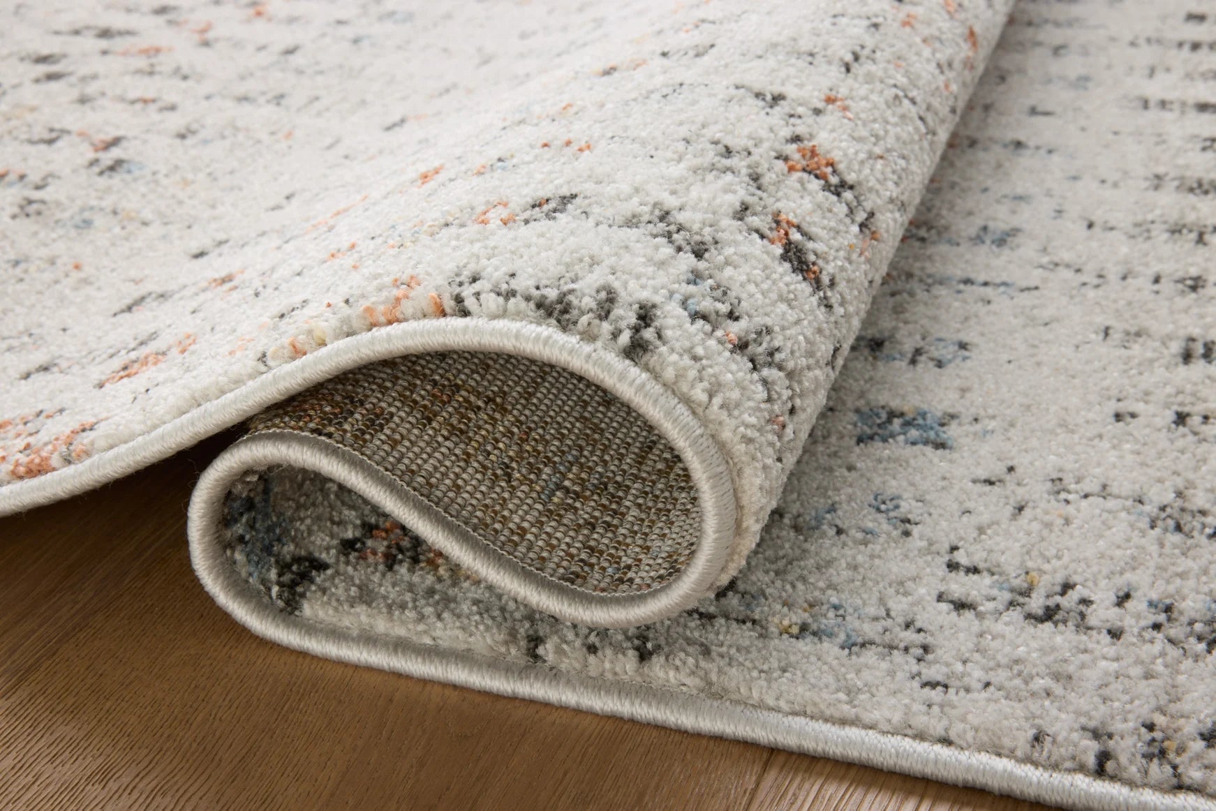 Grey area rug corner with stitched edge and short pile texture