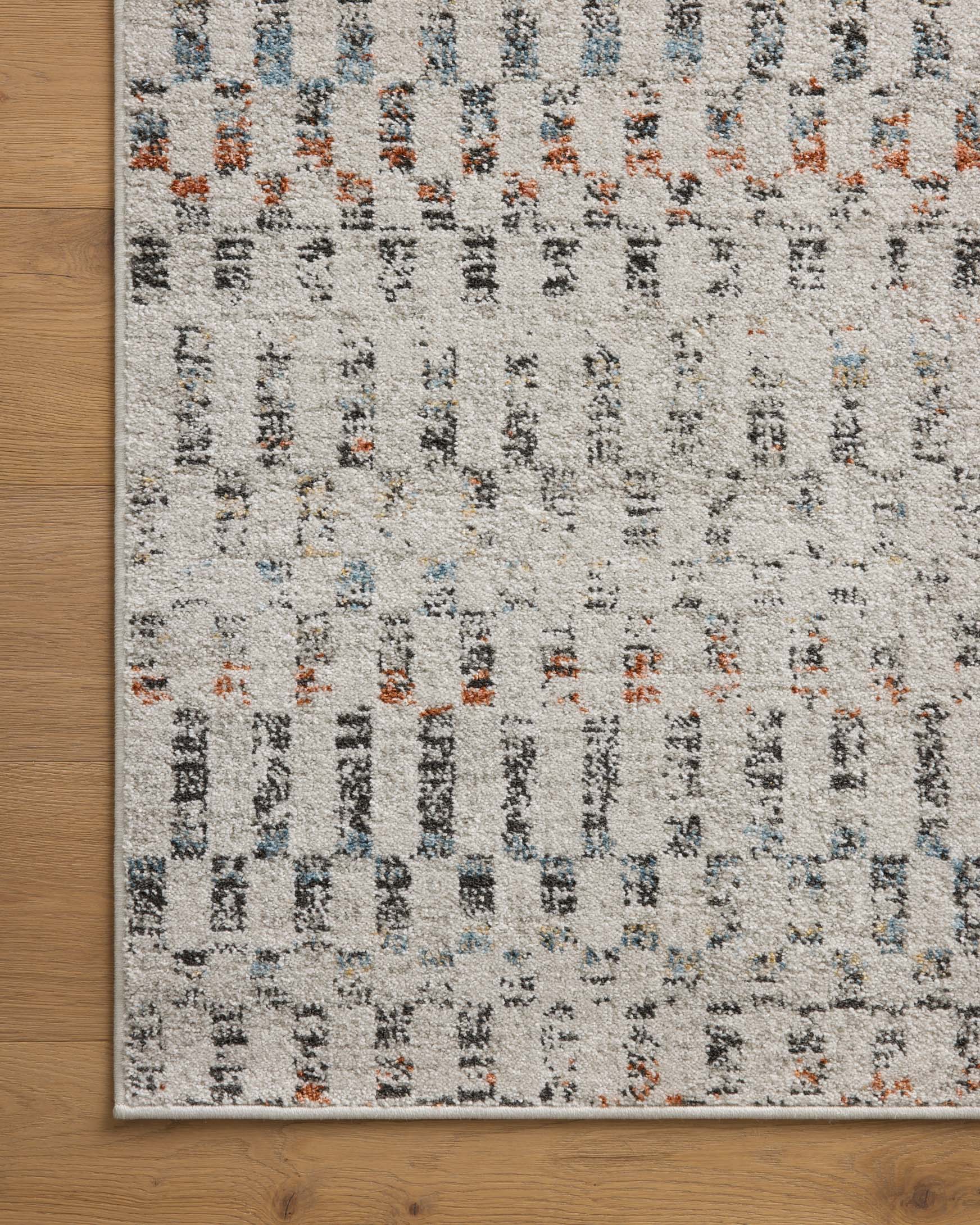 Grey accent rug laid flat on wood floor, rectangular border and geometric motifs