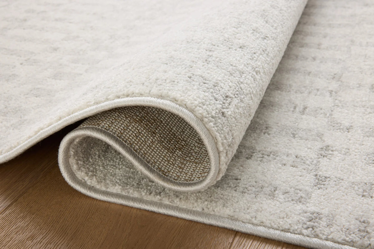 Ivory and grey area rug corner with visible binding and textured pile edge