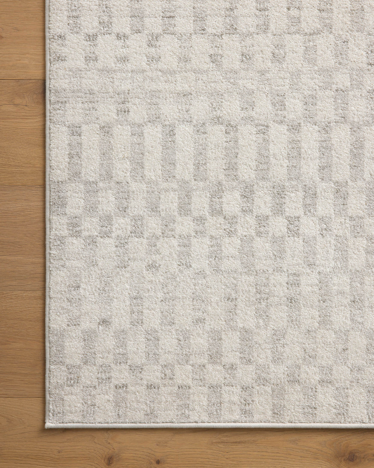 Ivory and grey area rug laid flat, showing dense geometric pattern and border