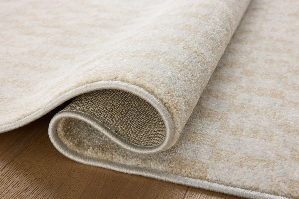 Close-up of ivory runner rug edge with bound border and low, textured pile.