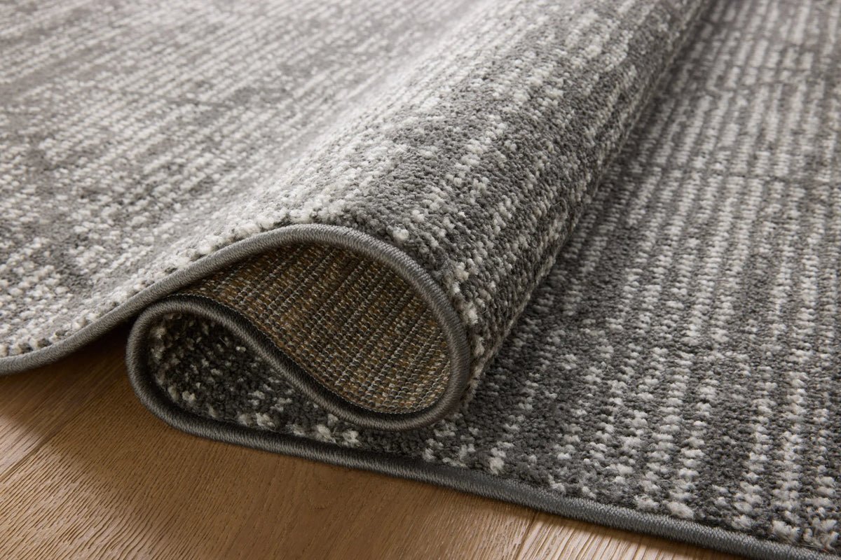 Corner detail of charcoal rug with ivory geometric texture and rounded serged edge trim.