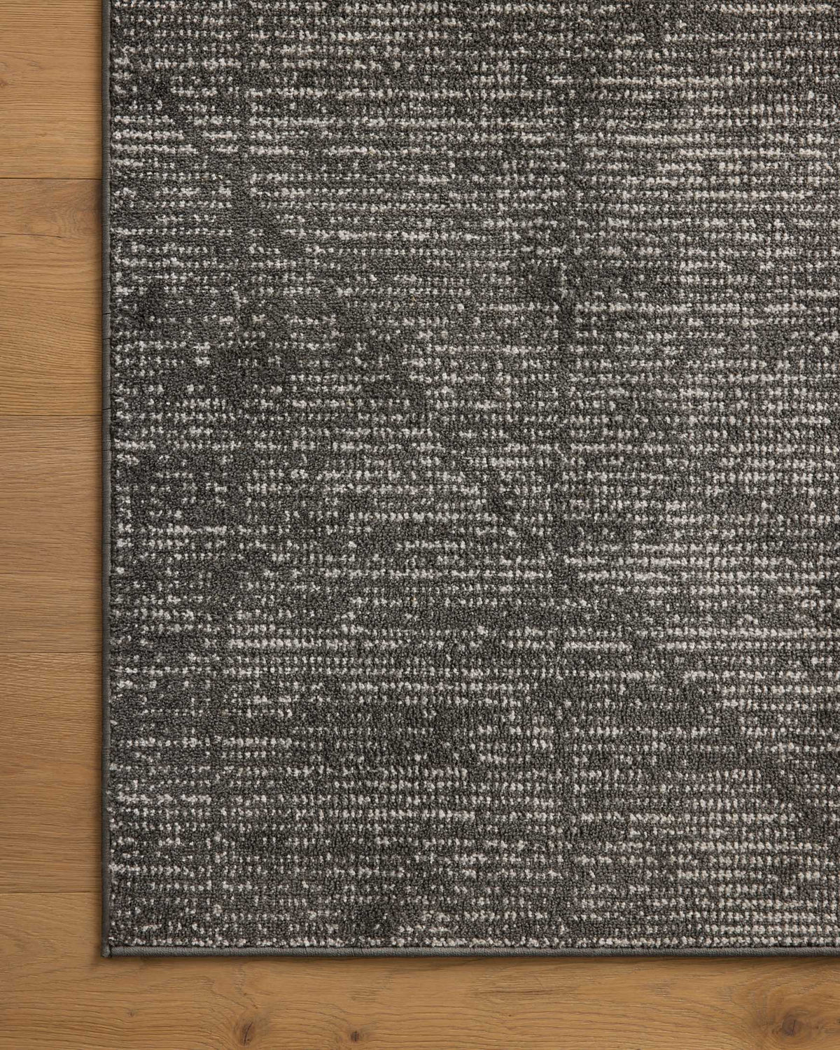 Charcoal and ivory accent rug edge on wood flooring
