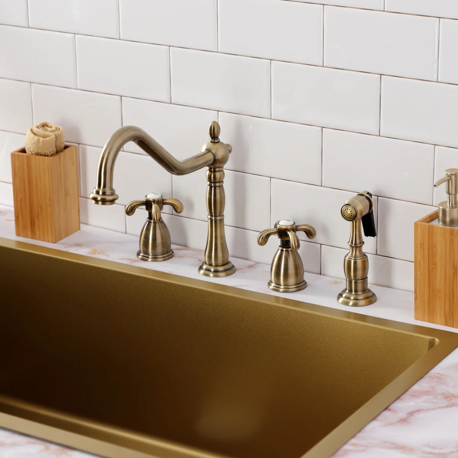 Antique brass kitchen faucet with gooseneck spout, sprayer head, and two deck handles