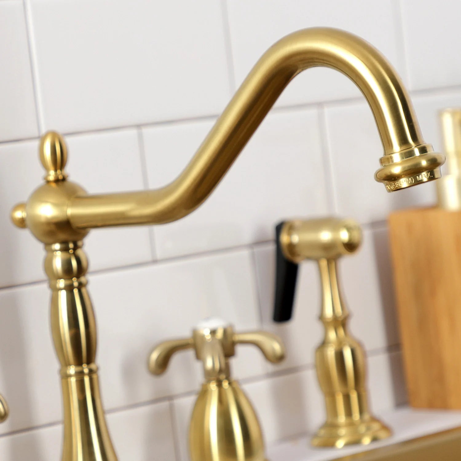 Brushed brass gooseneck faucet spout with handles on the sink deck