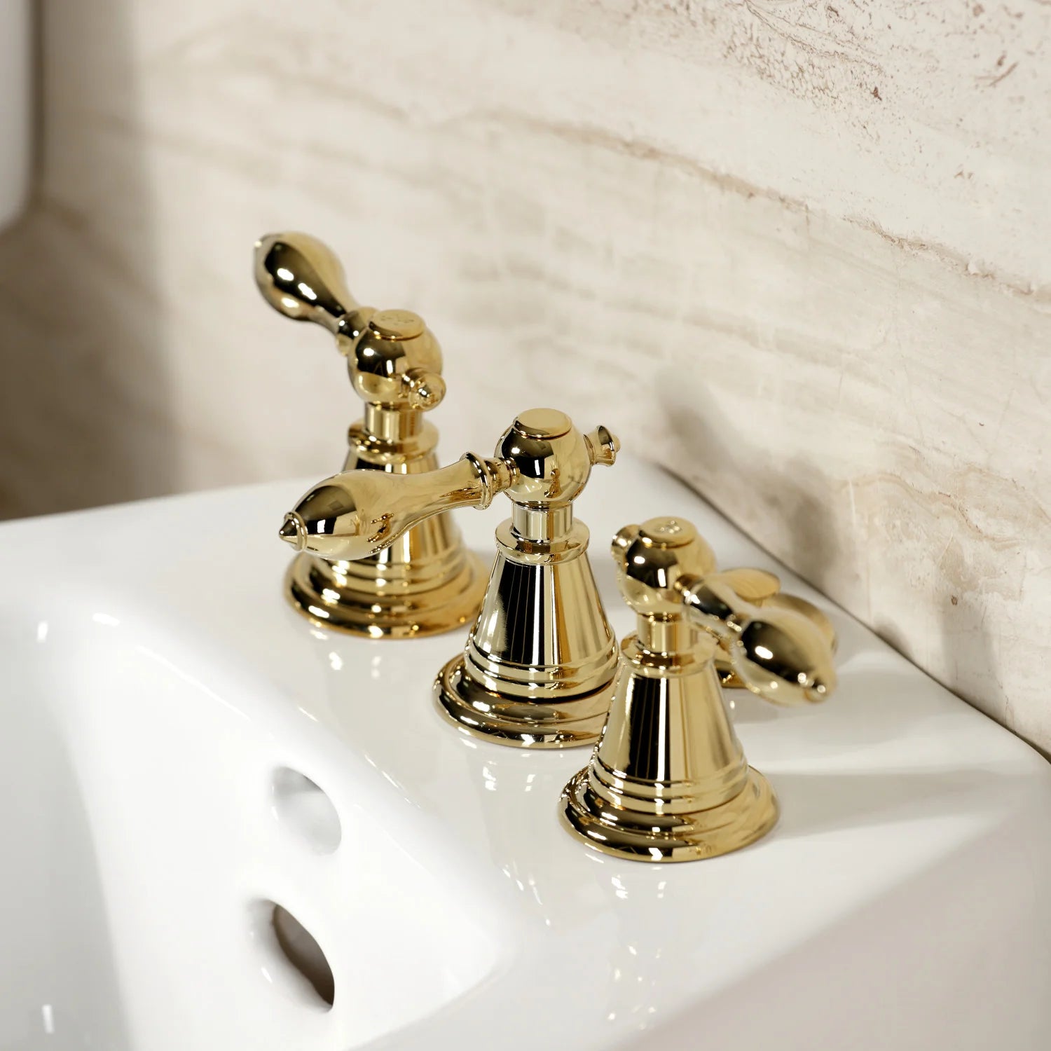 Three polished brass faucet handles with curved spout and round bases