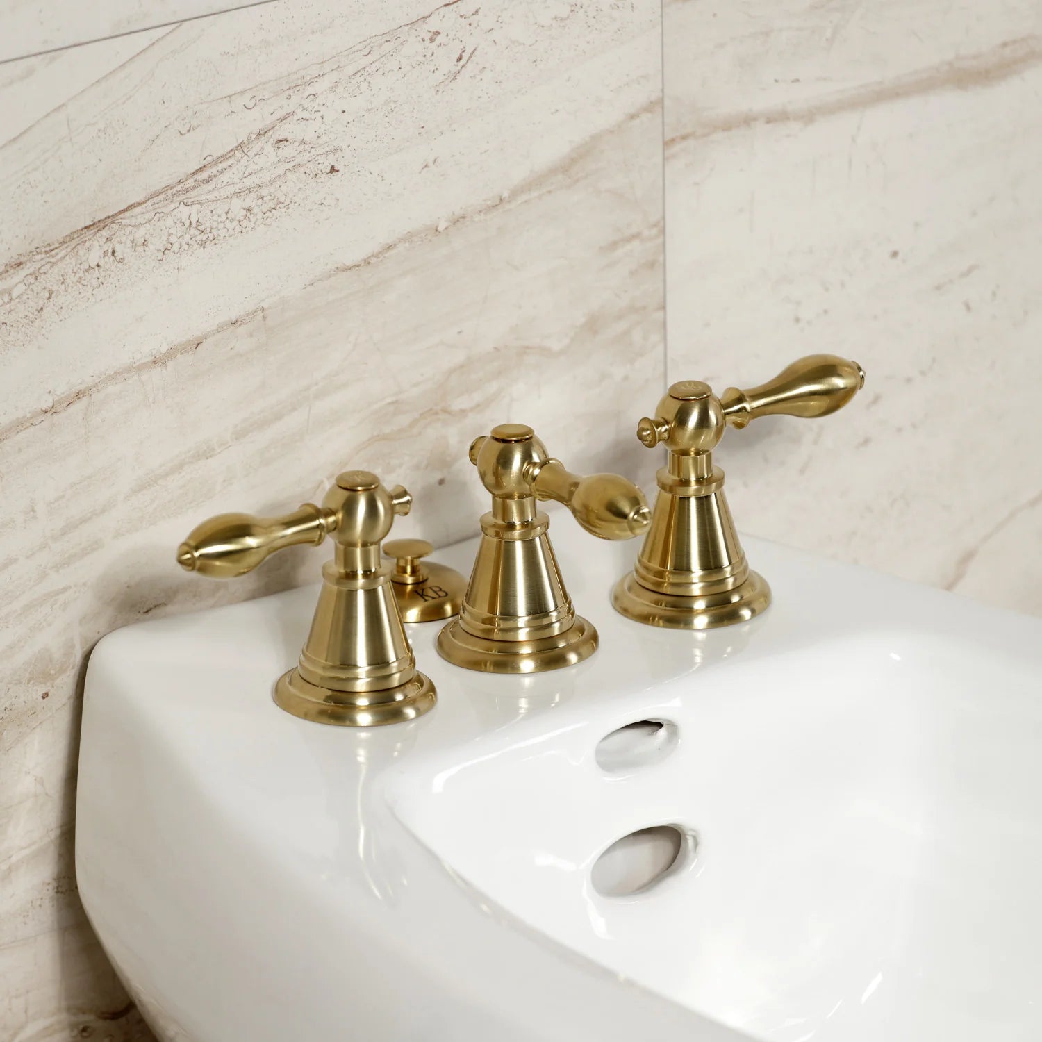 Brushed brass three-handle bidet faucet set with curved spouts and bases