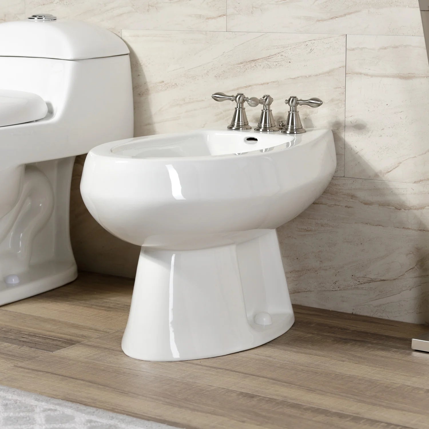 White bidet and brushed nickel three-handle faucet with center spout.