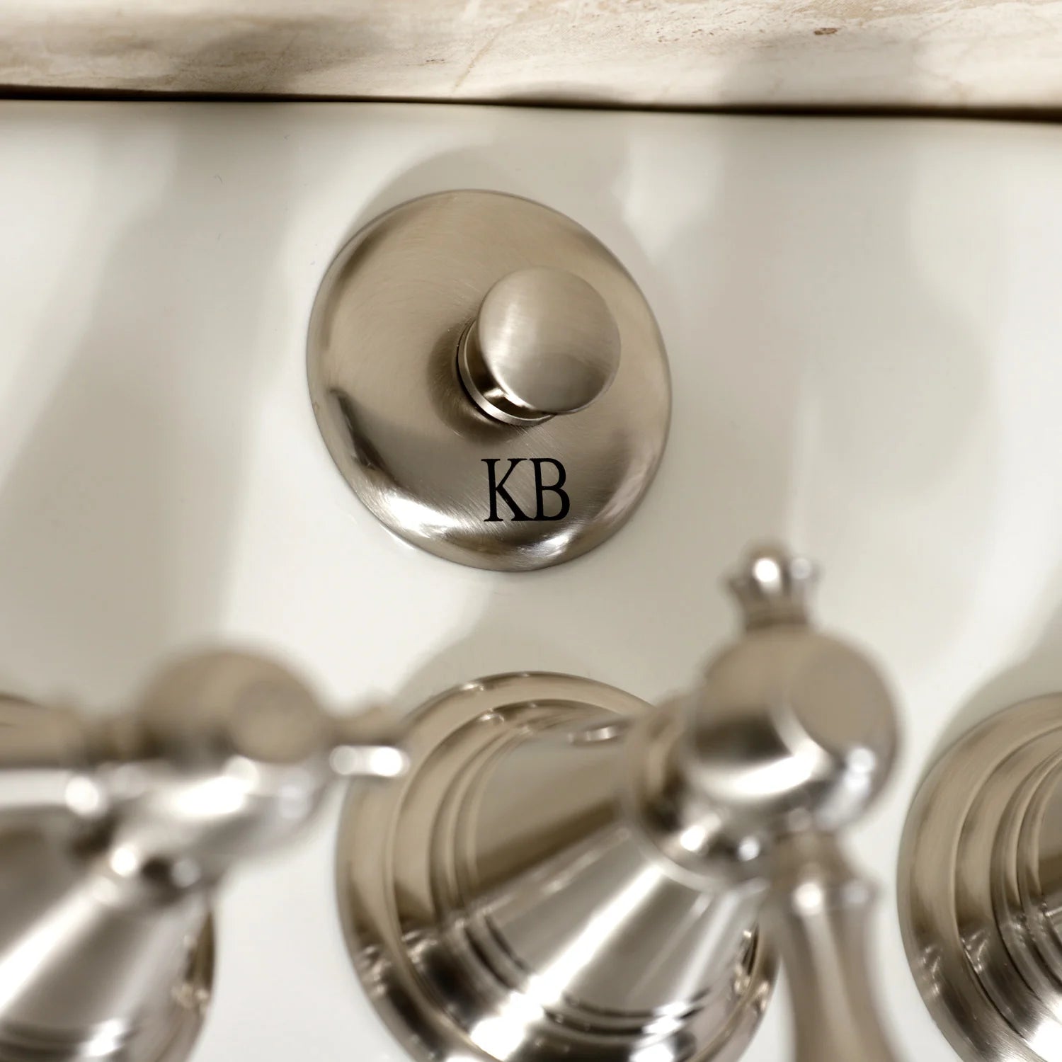 Brushed nickel Victorian bidet faucet escutcheon with KB logo and center handle.