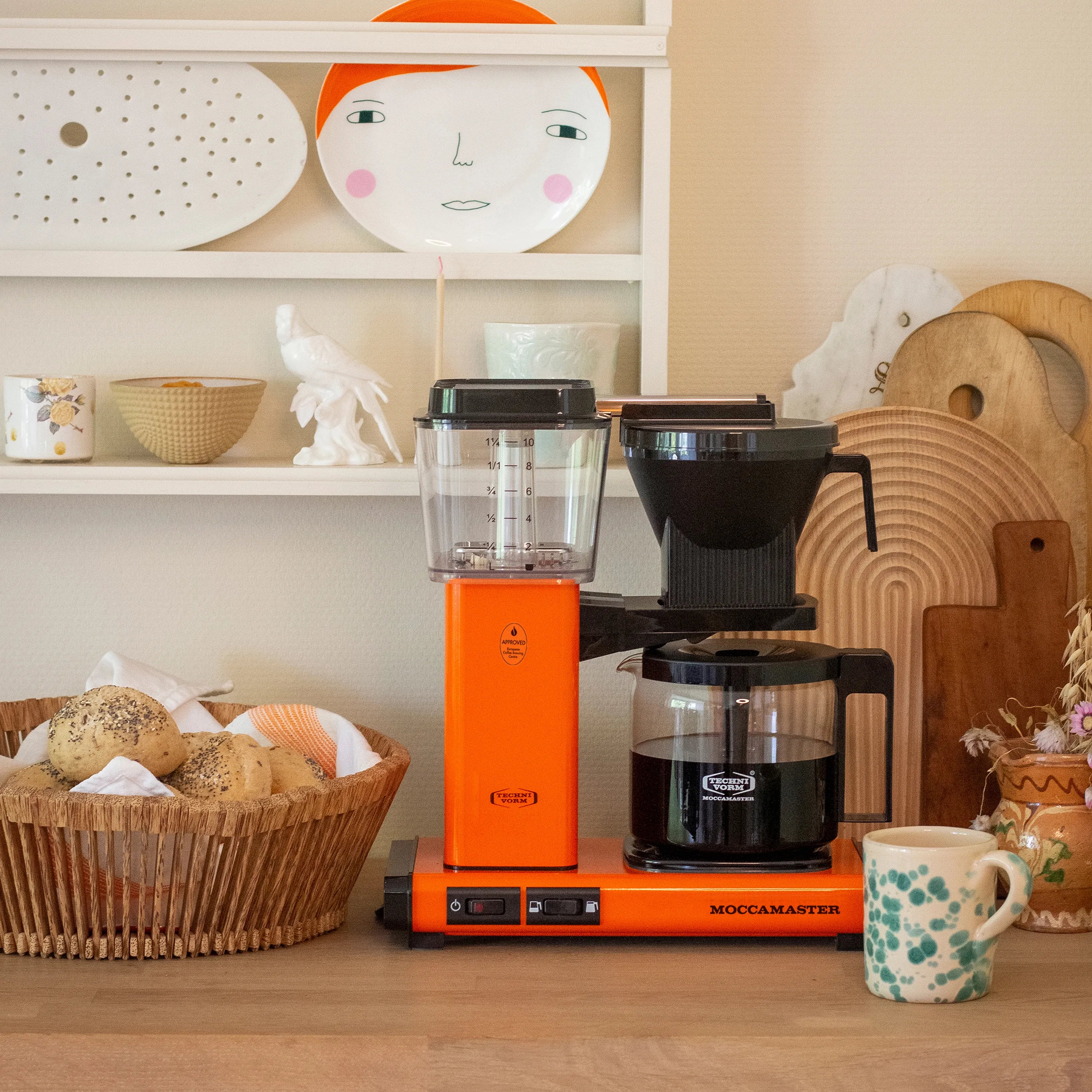 Orange 10-cup coffee maker with clear water tank, black grinder, and glass carafe