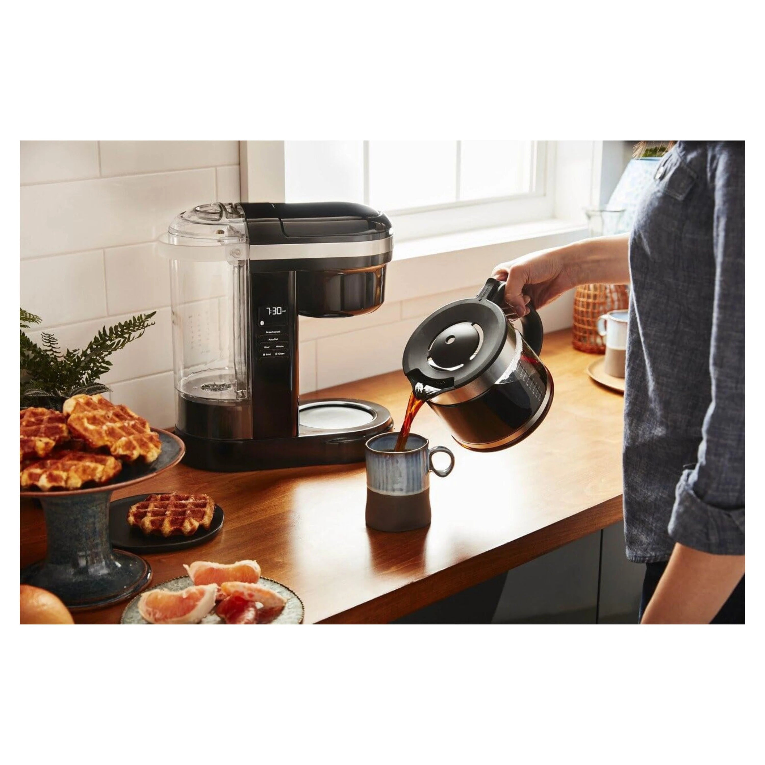 KitchenAid 12-cup drip coffee maker matte charcoal gray with open lid while hand pours