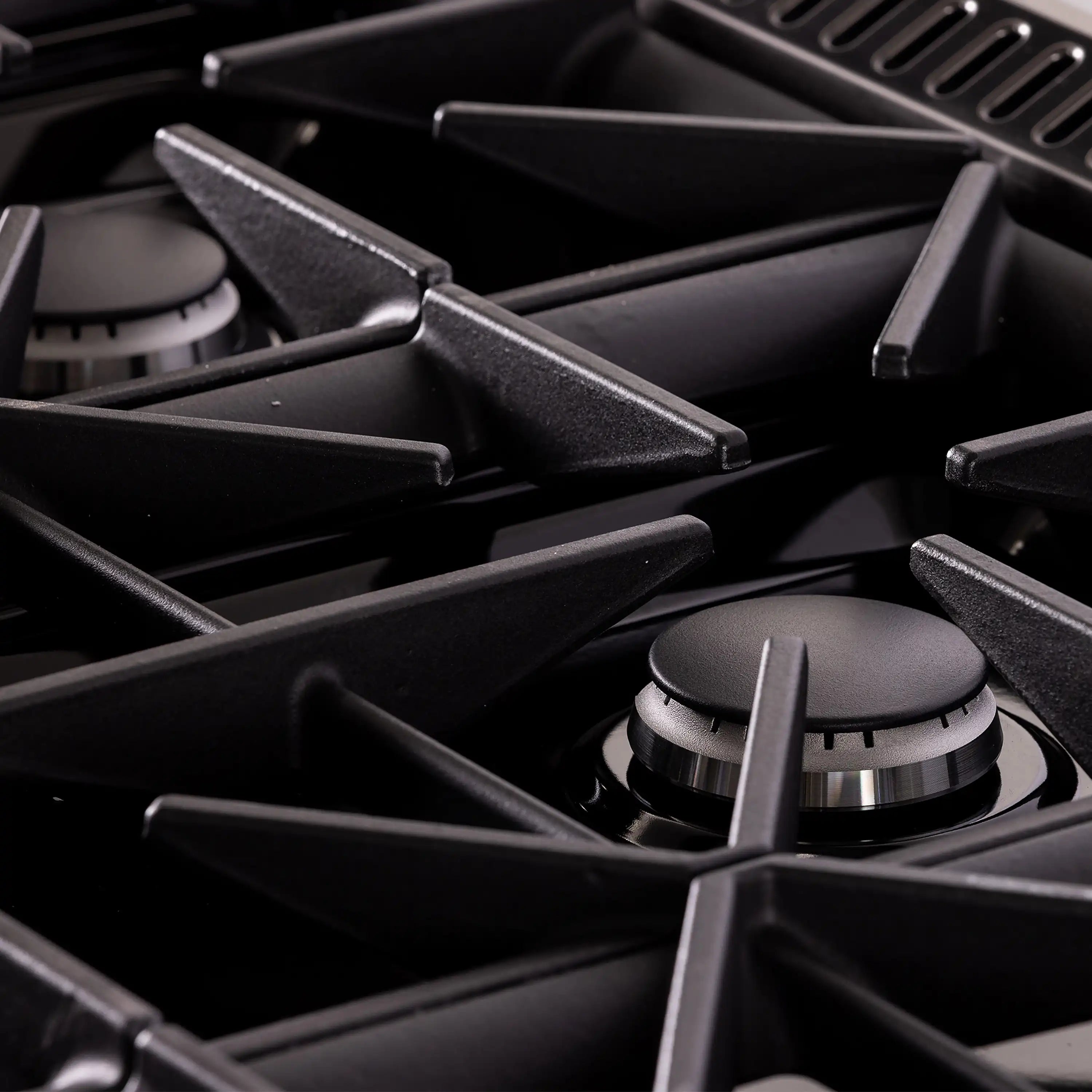 Dual fuel range burner grates and black cast supports, close-up