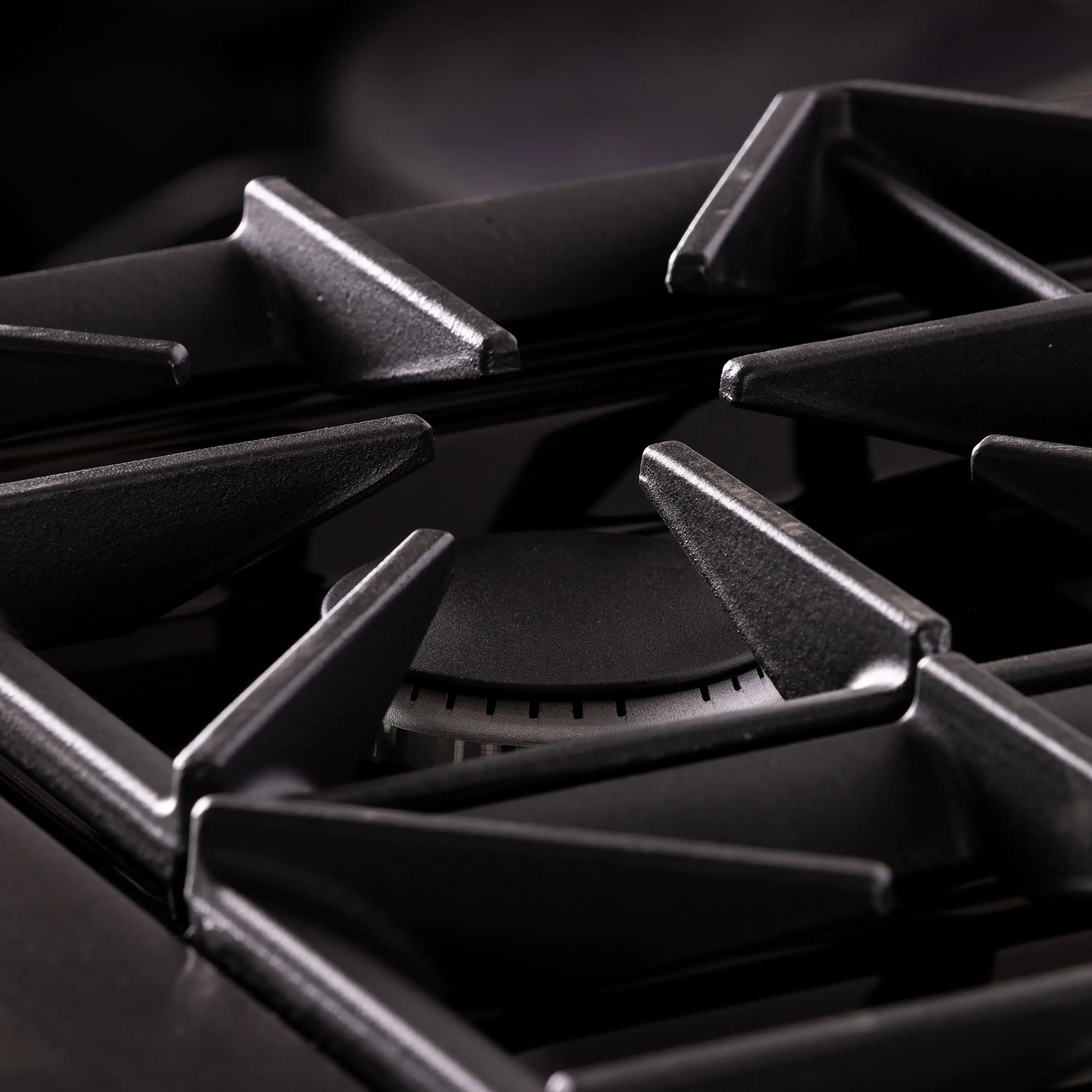 Gas range burner grates close-up with black cast supports and circular burner cap