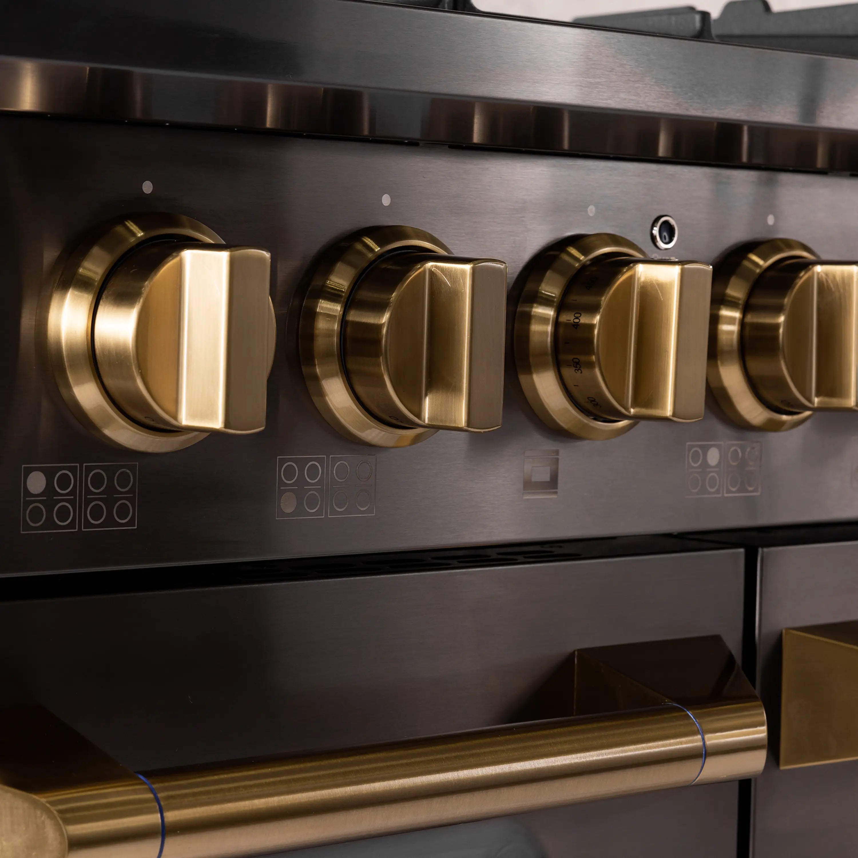 Stainless steel gas range control panel with brass burner knobs and display buttons