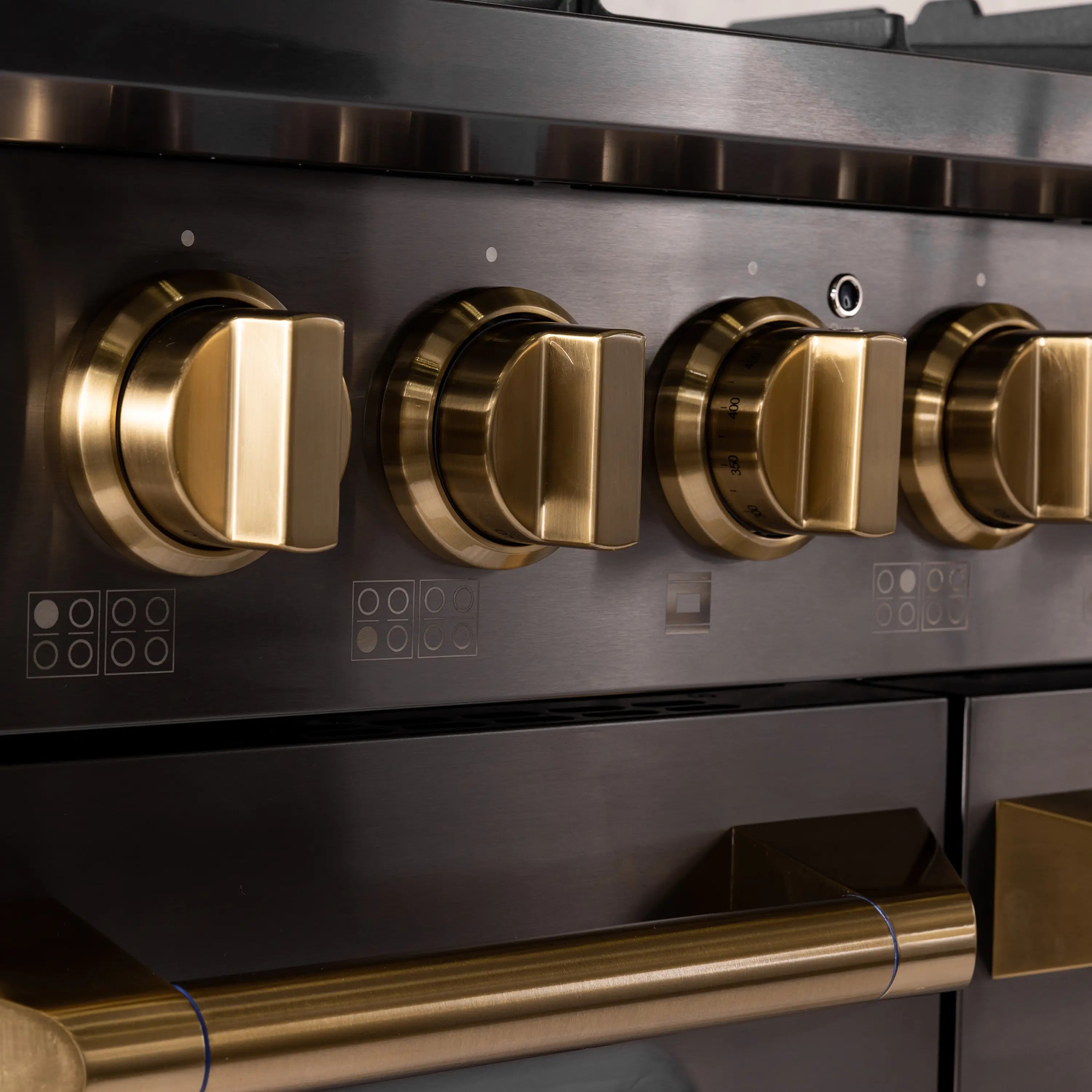 Close-up of gold control knobs and burner settings on stainless dual fuel range