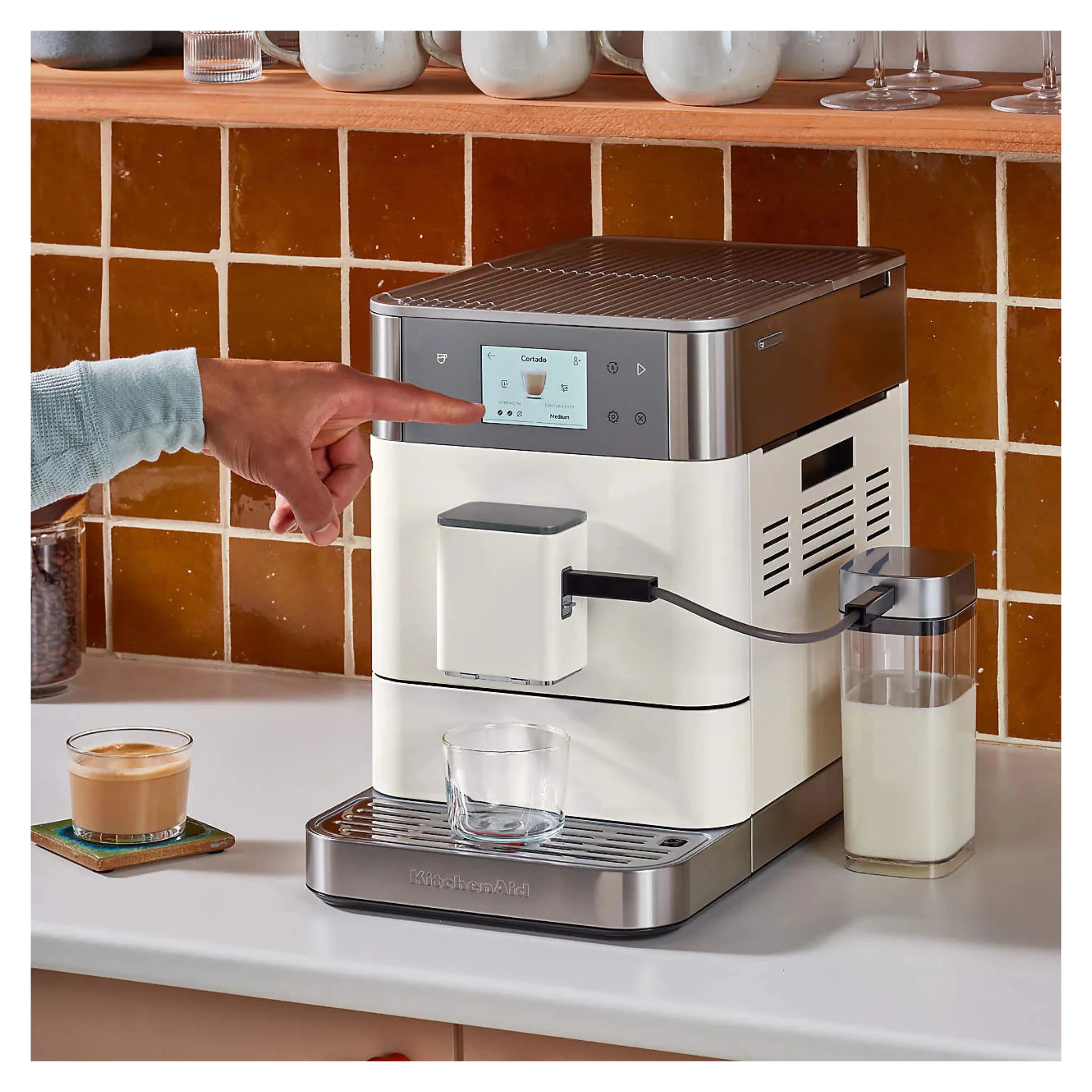 Porcelain white espresso machine dispensing into a glass cup with milk container