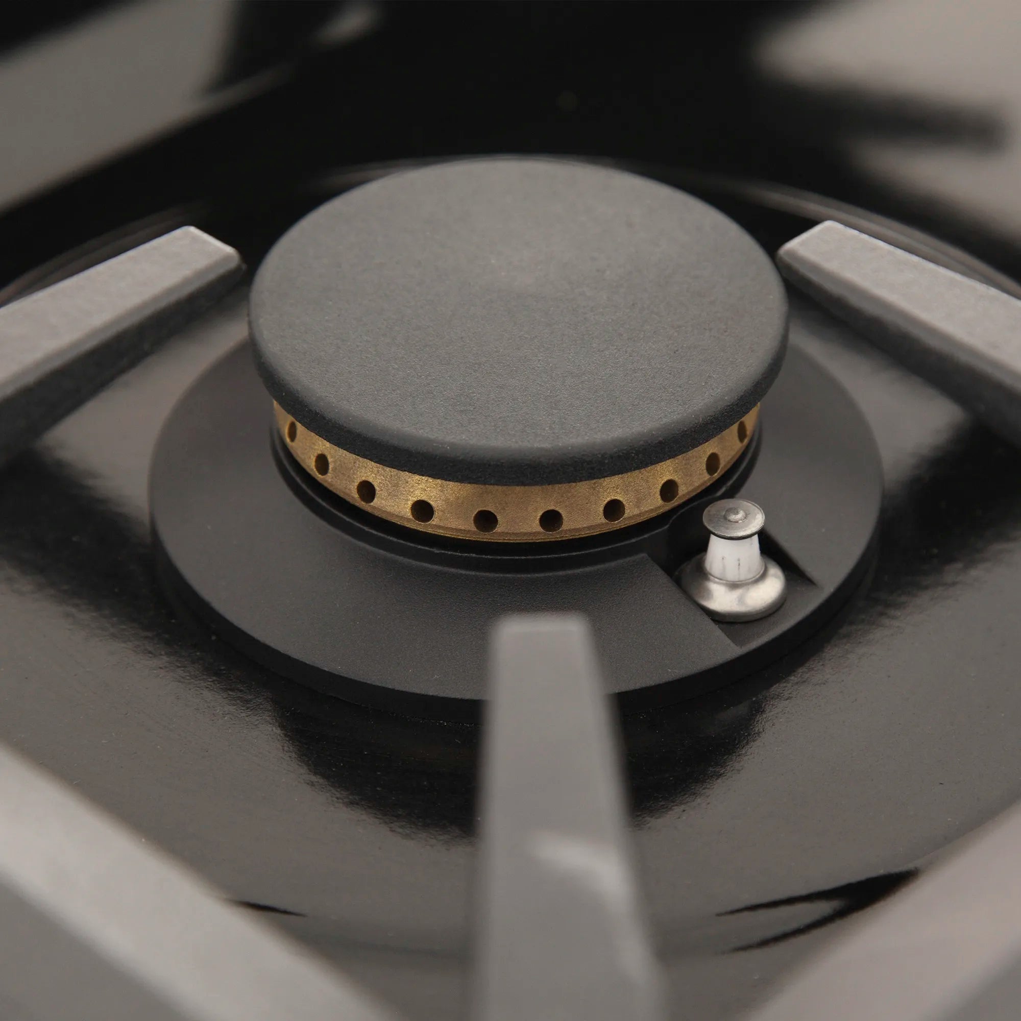 Black gas cooktop burner with round cap and metal control knob