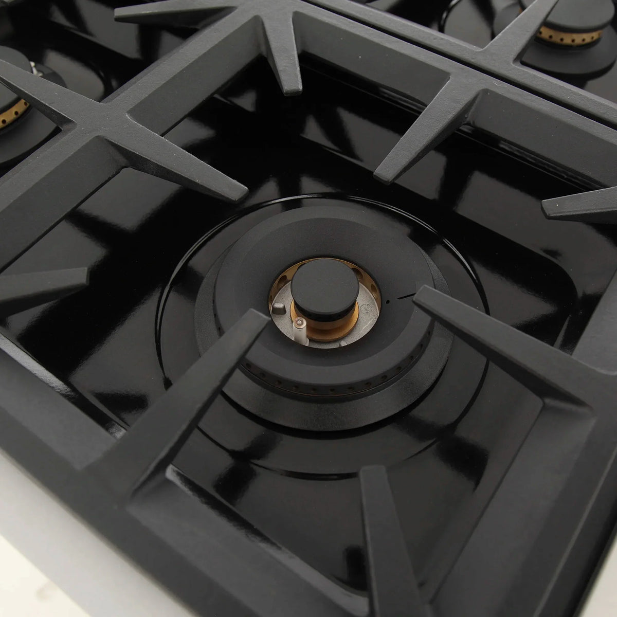 Black gas burner with circular cap and grate on the cooktop