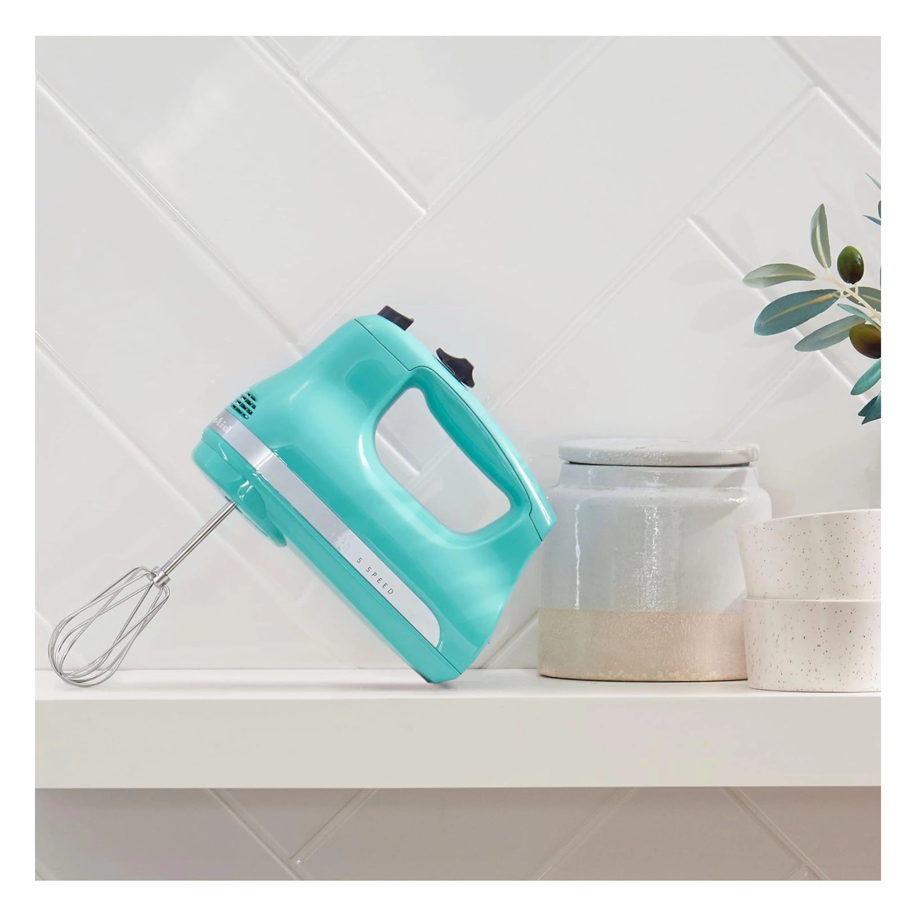 Aqua Sky KitchenAid hand mixer resting on countertop with bowl nearby