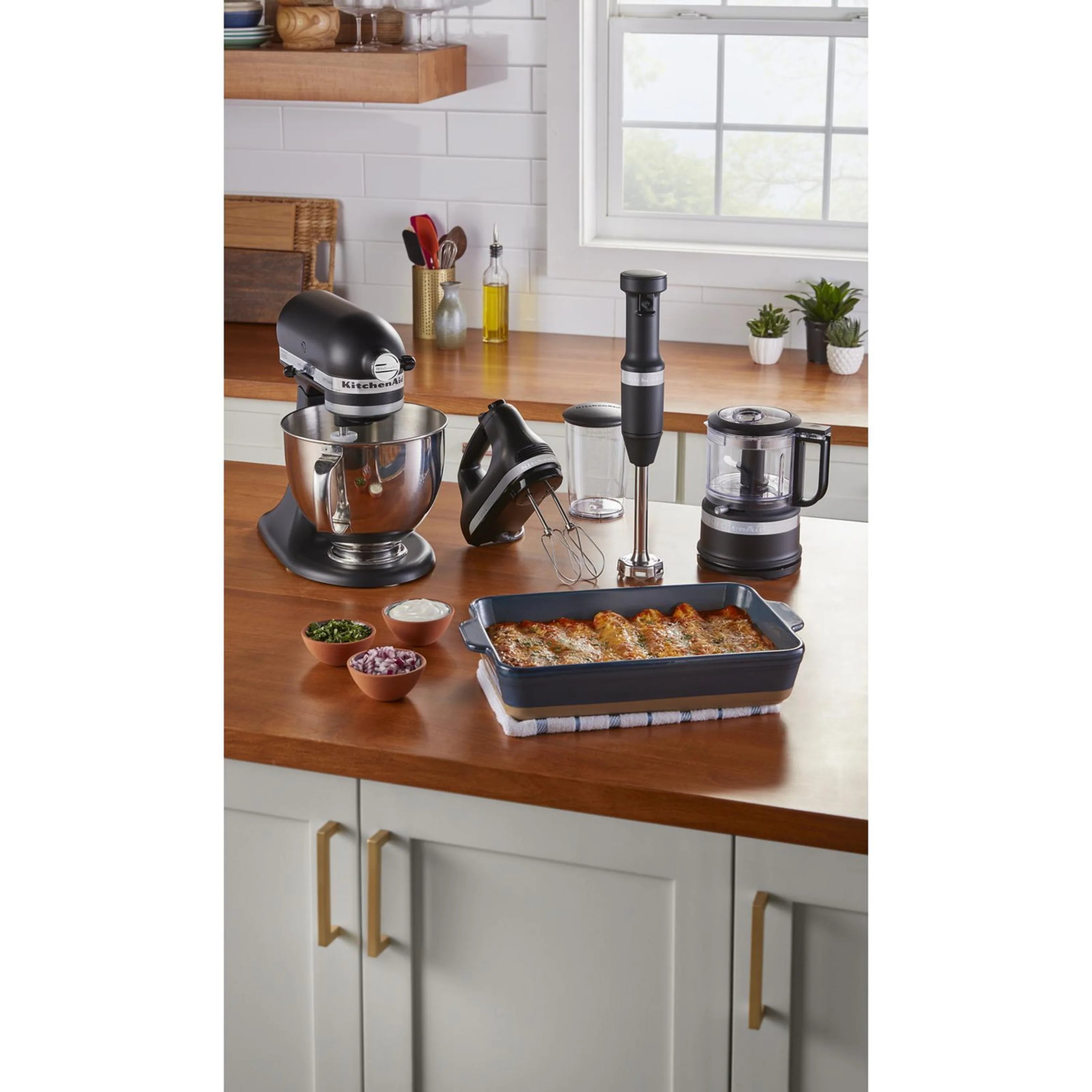 Black matte hand mixer on kitchen counter with stand mixer nearby